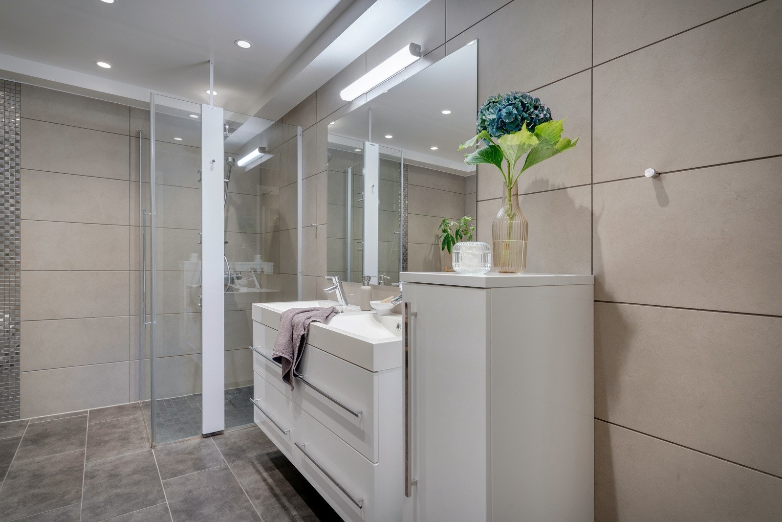 Badet er utstyrt med foldedører i dusj, veggtoalett og baderomsinnredning med heldekkende servant samt belyst speil Galleribilde
