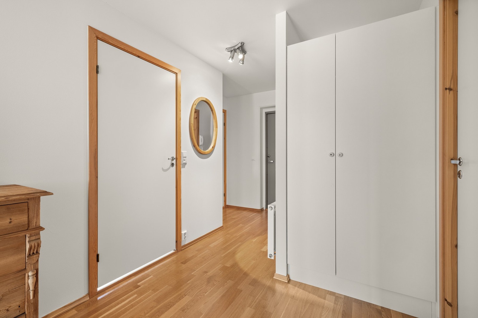 Fra entréen fører en romslig gang videre innover i leiligheten, som binder rommene sammen på en praktisk og luftig måte, samt gir ekstra plass for lagring og oppbevaring i garderobeskap. Galleribilde