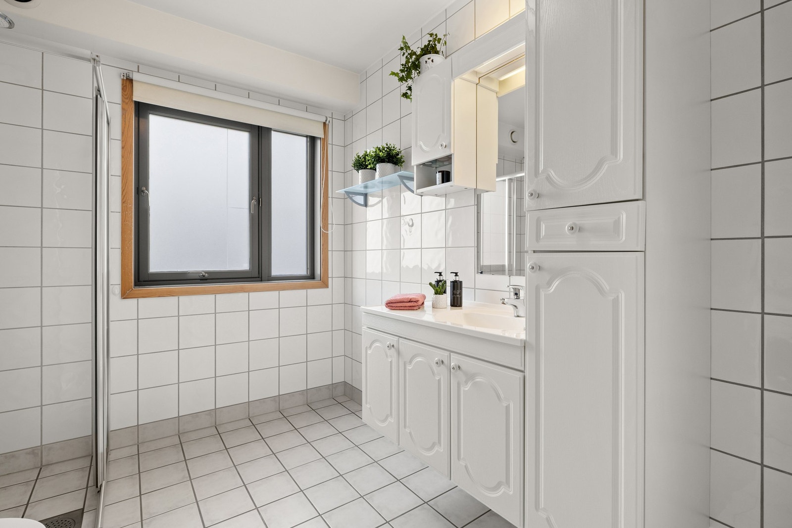 Lyst og romslig baderom med fliser på gulv og vegger, samt malte flater i himling. Galleribilde