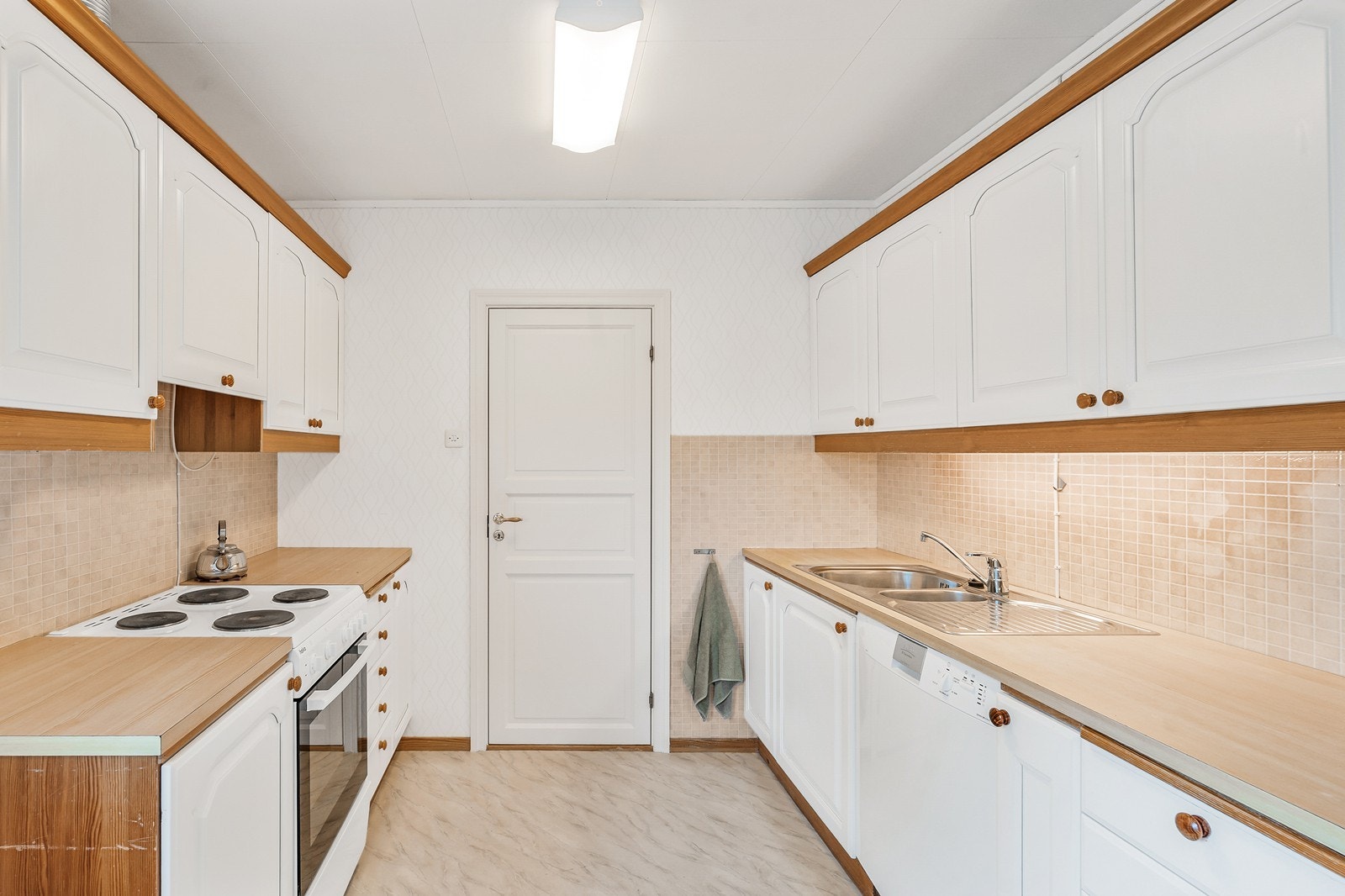 Kjøkkenet har godt med skap- og benkeplass på begge sider Galleribilde