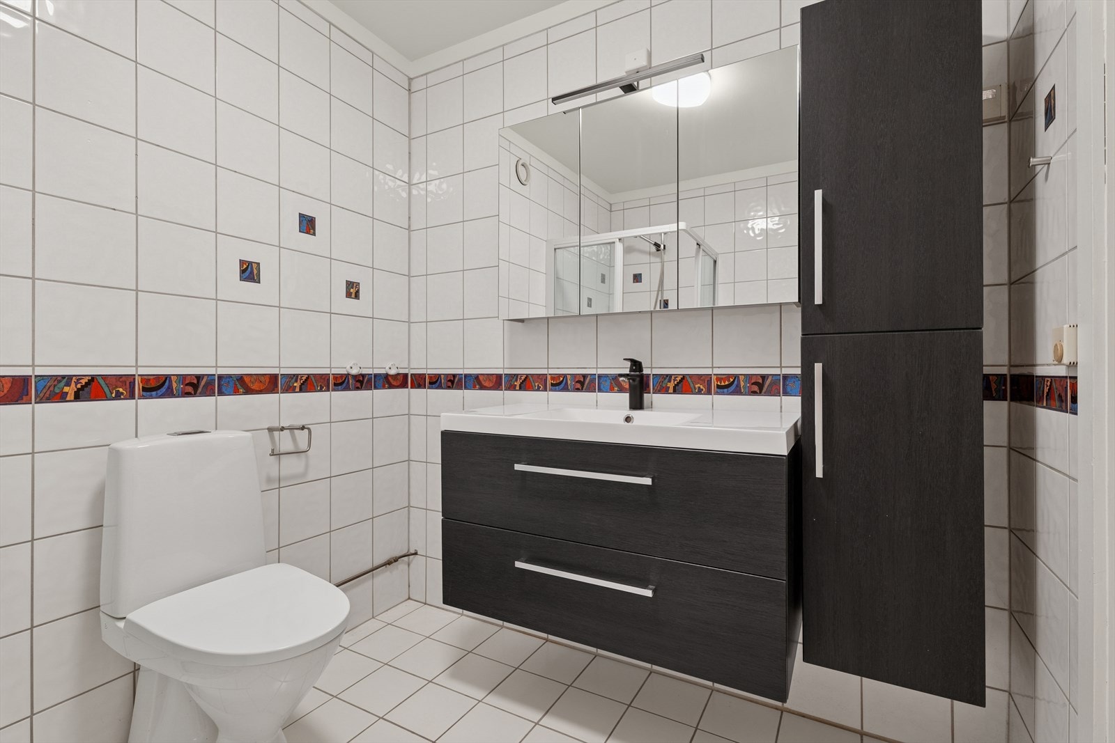 Over servanten er det et speilskap med belysning, samt et veggmontert skap som gir ekstra lagringsmuligheter. Galleribilde