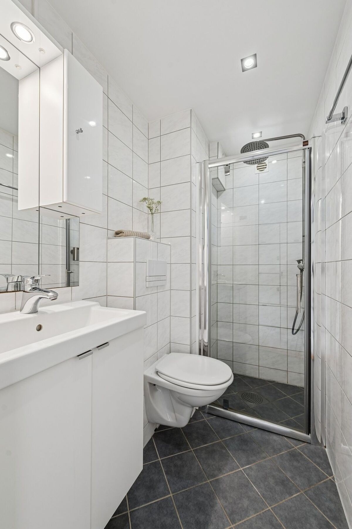 Leiligheten har to flislagte bad, noe som gjør den velegnet for familier. Her vises badet i tilknytning til entréen med dusjsone. Galleribilde