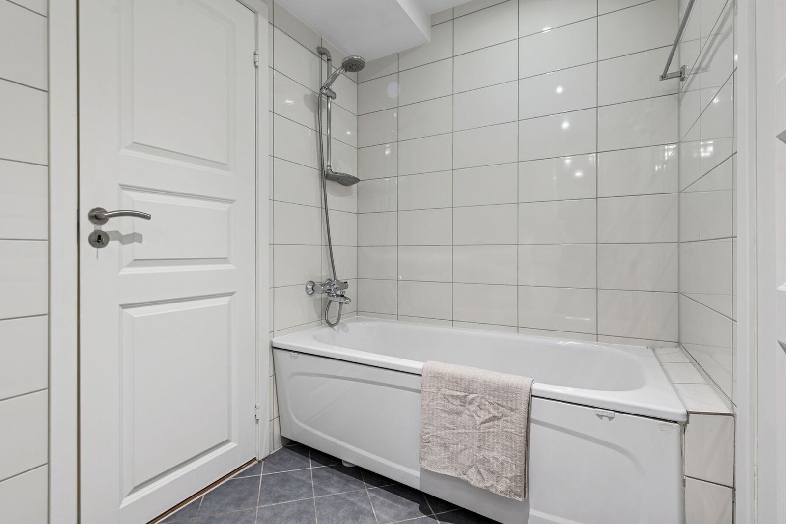 Hovedbadet har badekar med dusj på vegg. Badene er innredet i tidløse hvite og grå toner, som gir en behagelig start på dagen. Galleribilde