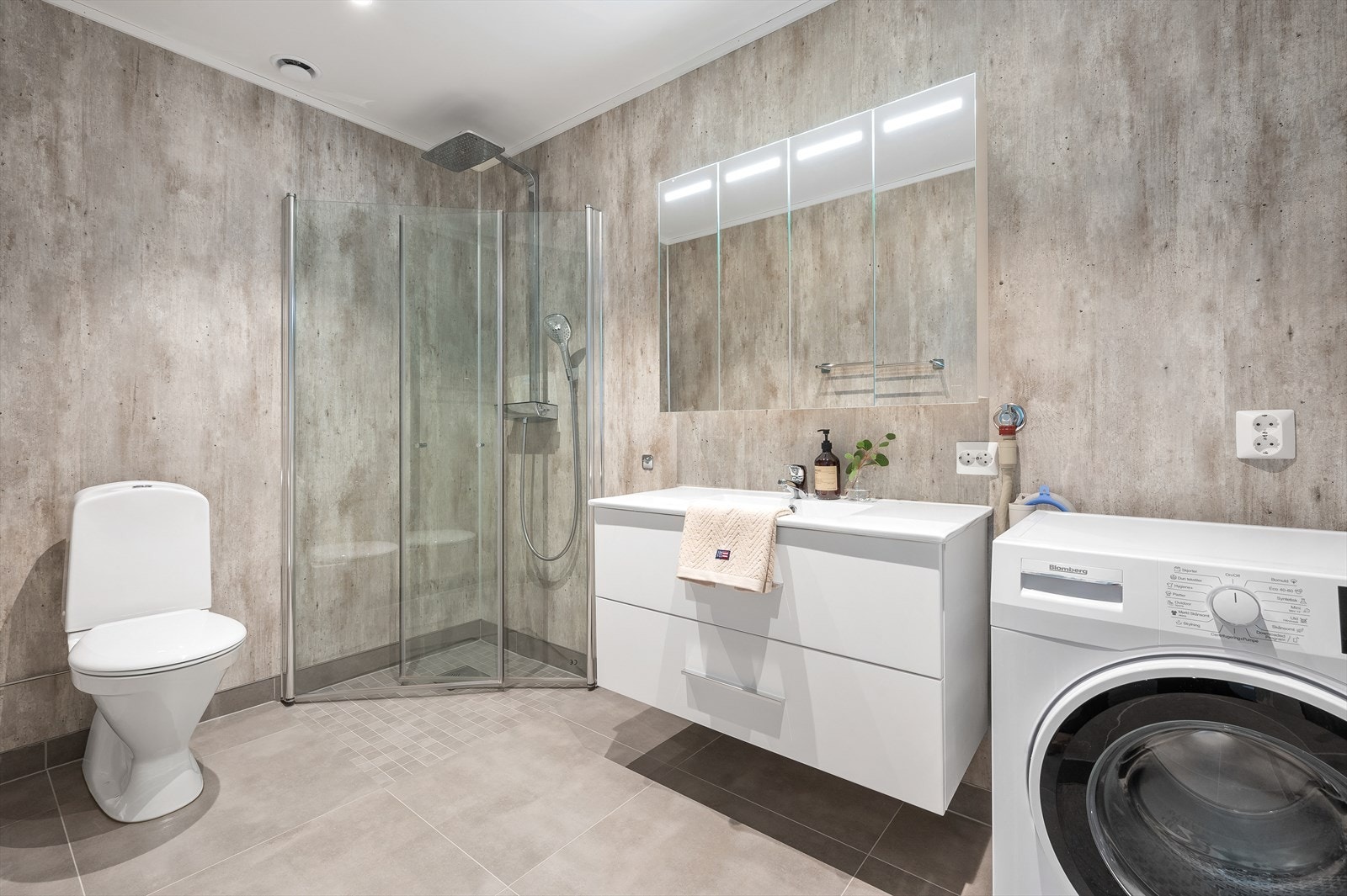 Praktisk bad i 2. etasje med dusjhjørne med innfellbare dusjvegger, lys baderomsinnredning med skuffer, overspeil og opplegg til vaskemaskin og tørketrommel! Galleribilde