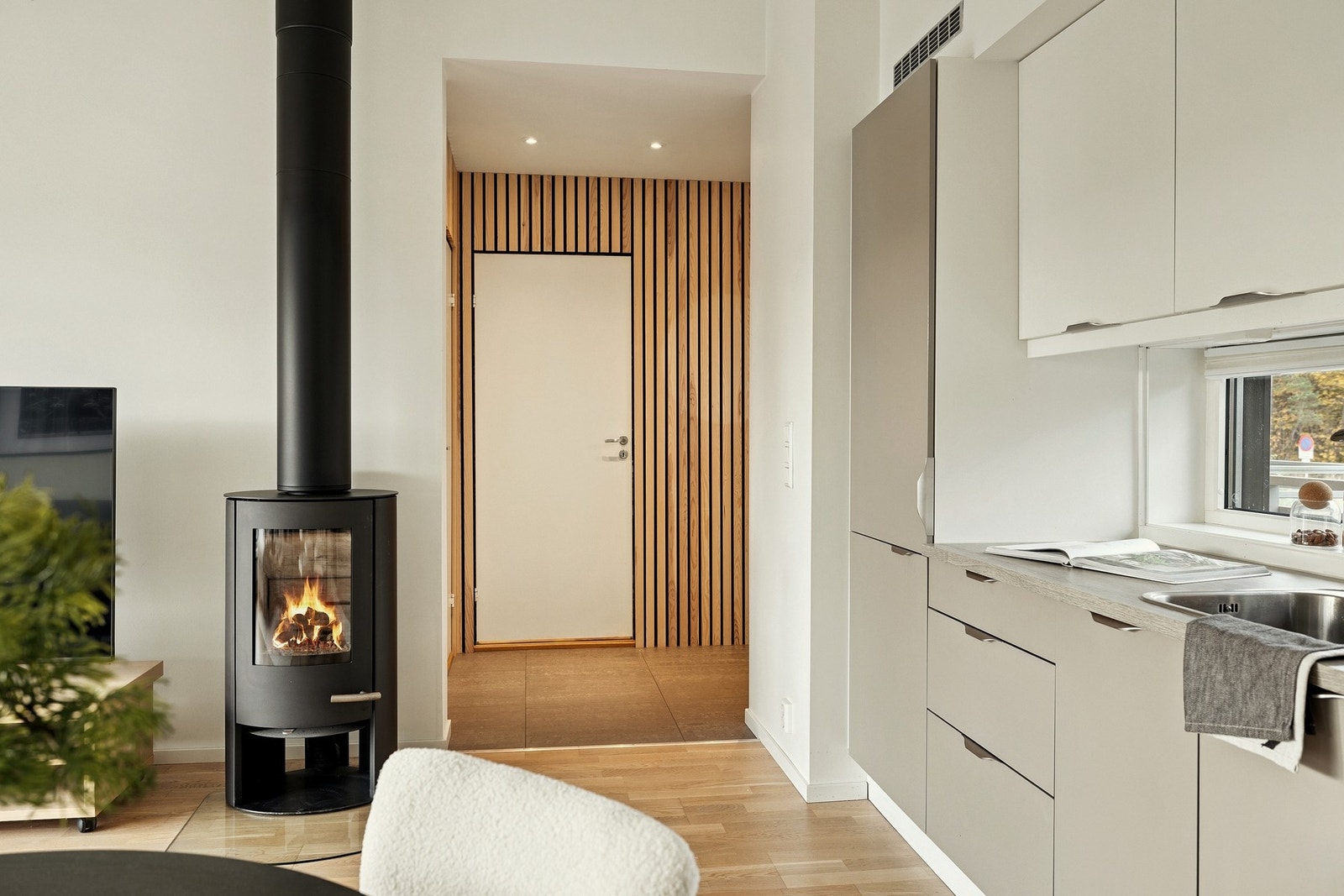 Kjøkken og entré i tilknytning til stue. Peisovn gir både varme og et hyggelig innslag i rommet. Galleribilde