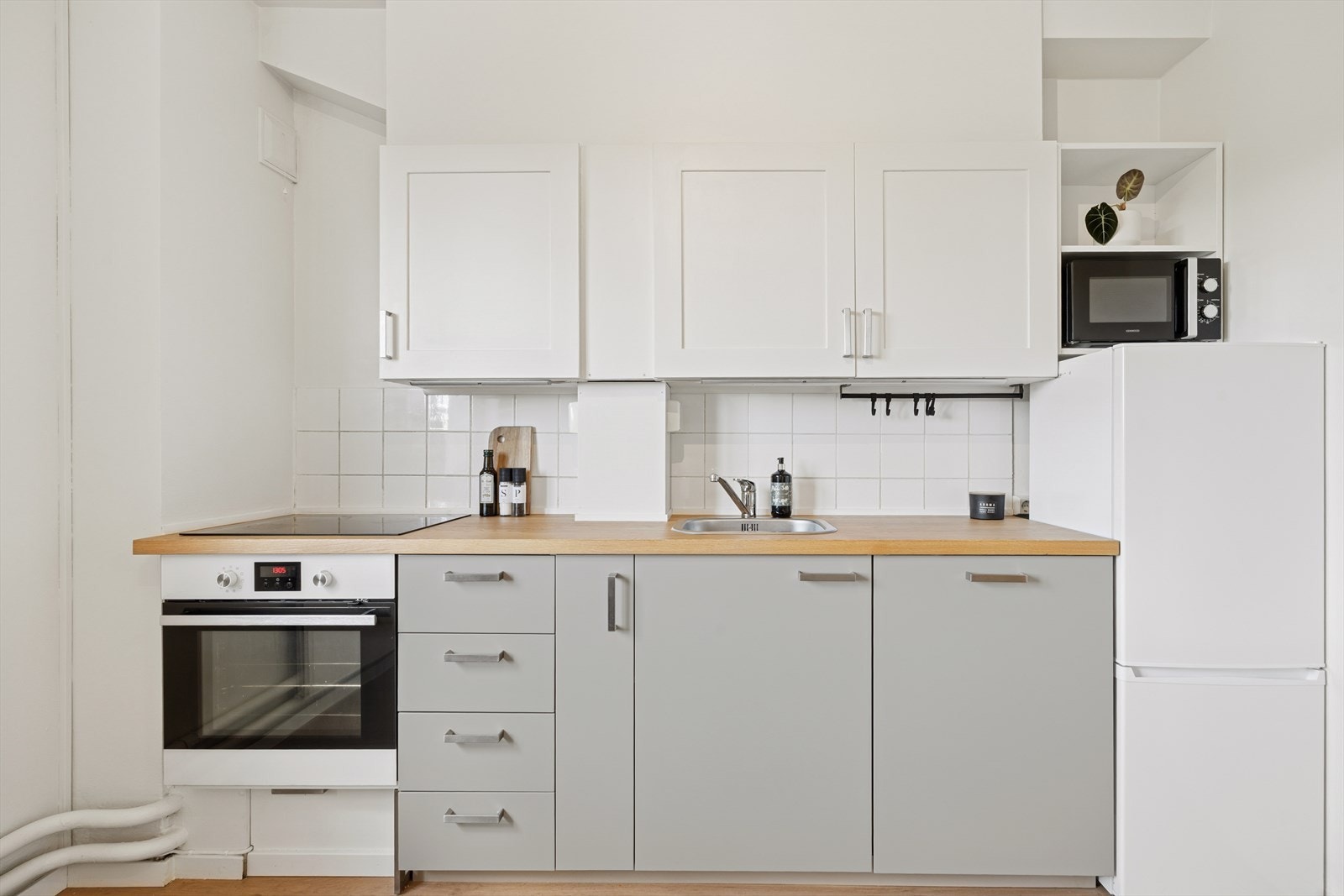 Kjøkkenet er utstyrt med belysning under overskap, fliser på vegg over benkeskap og en laminat benkeplate med nedfelt kum i rustfritt stål. Galleribilde