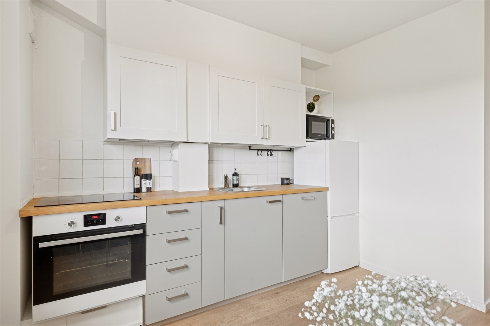 Kjøkkenet har en innredning med glatte fronter på benkeskap og profilerte fronter på overskap. Galleribilde