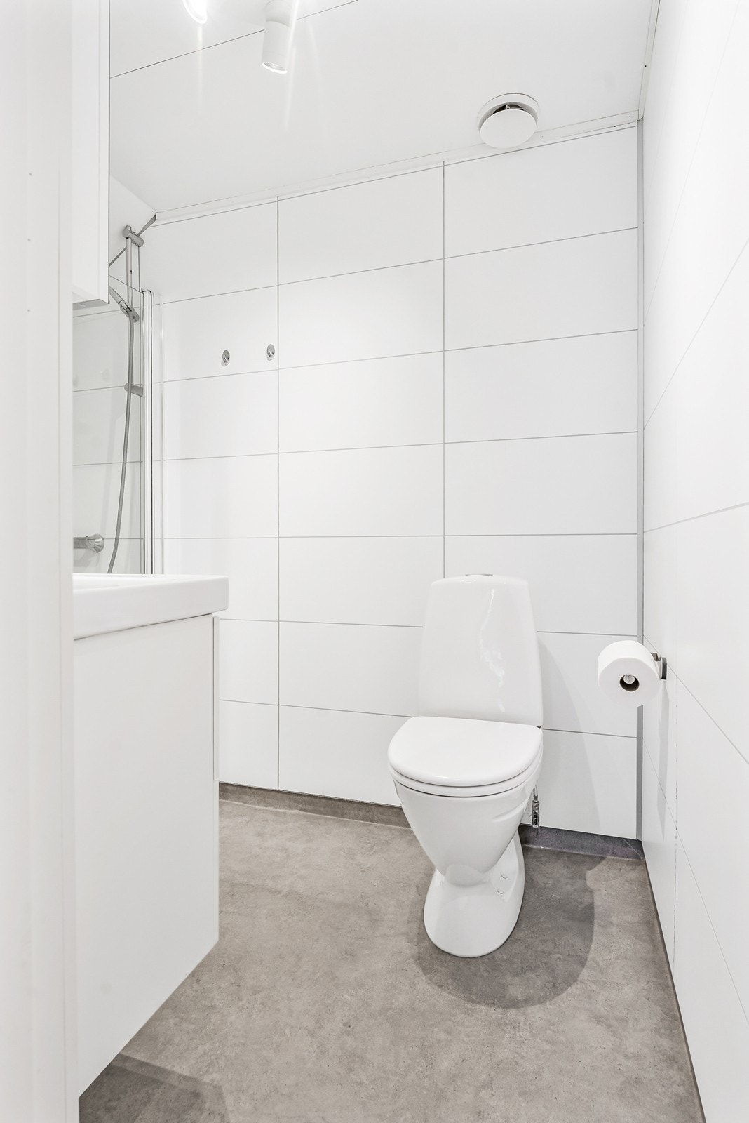 Badet inneholder dusjhjørne med glassdør, servant med skuffeinnredning og speilskap, samt gulvstående toalett. Galleribilde