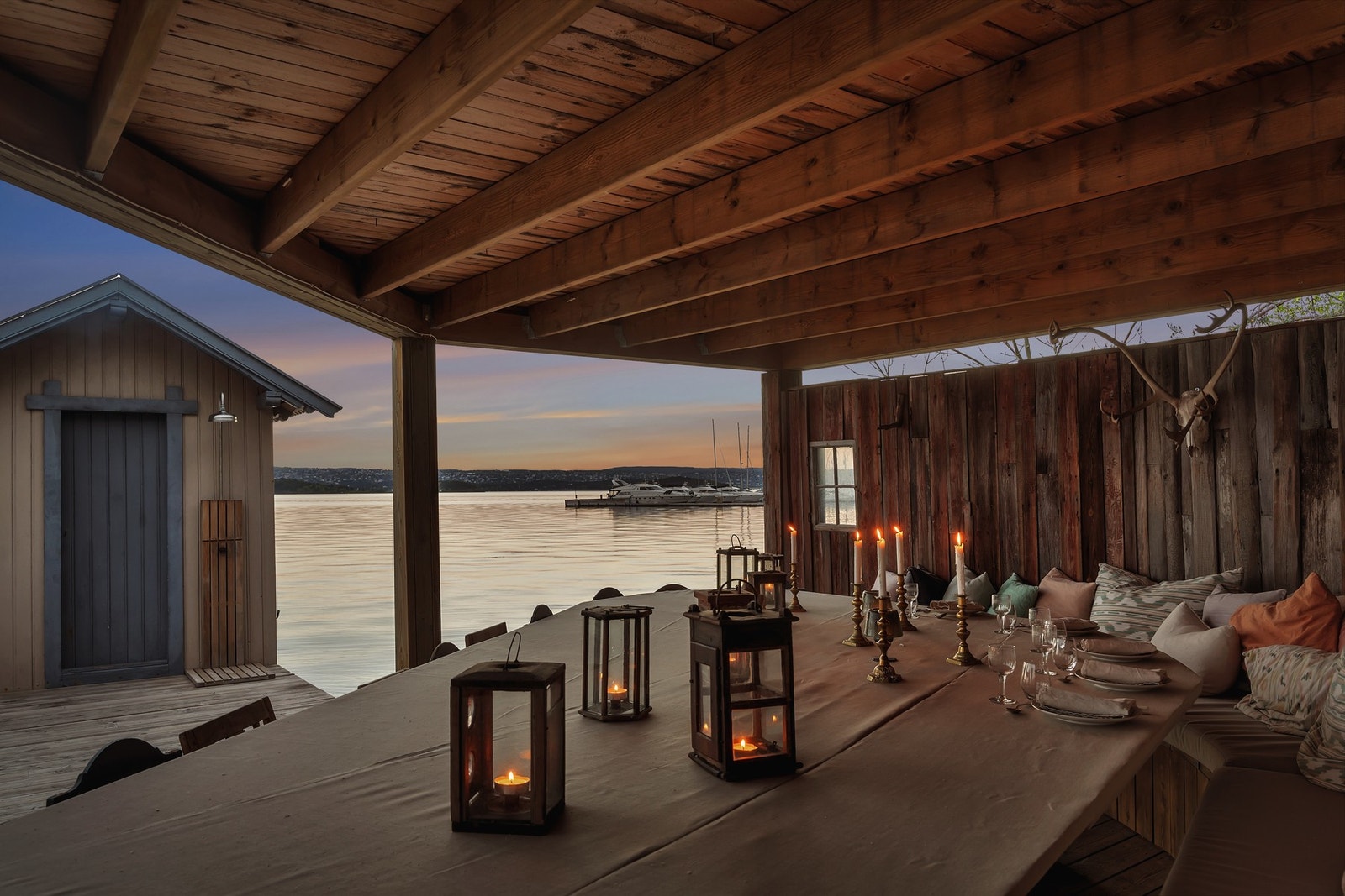 Stemningsfull uteplass med takoverbygg - perfekt for sene sommerkvelder ved sjøen med levende lys, utsikt og lune omgivelser. Galleribilde