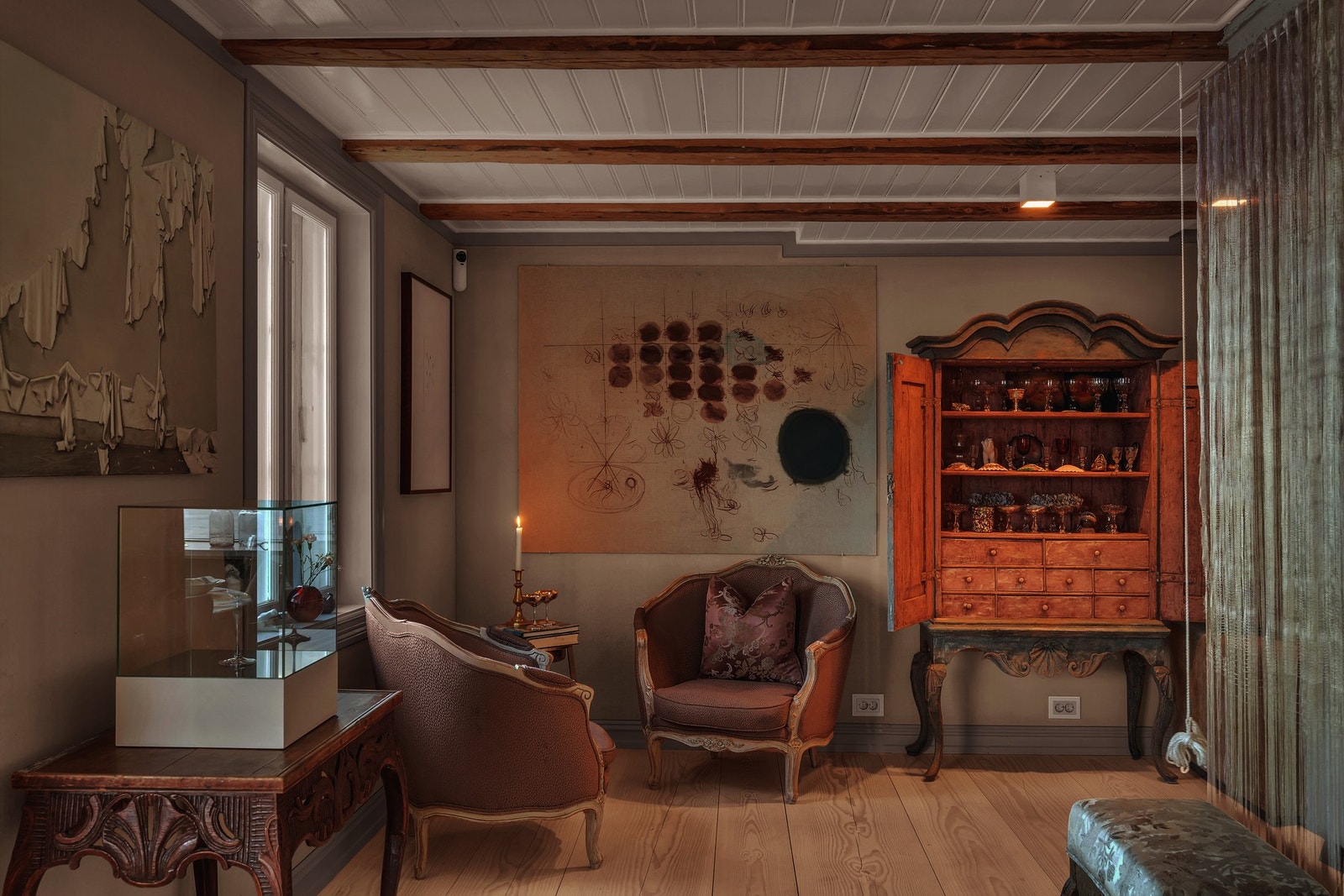 Elegant og kunstnerisk innredet salong med antikke møbler, varme nyanser og vakre detaljer som skaper en tidløs og rolig atmosfære. Galleribilde