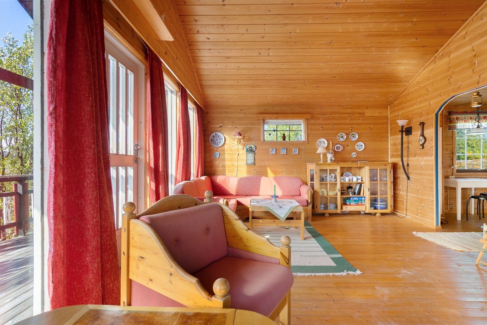 Hyggelig stue med tregulv, panelvegger og store vindusflater som skaper en ekte hyttefølelse Galleribilde