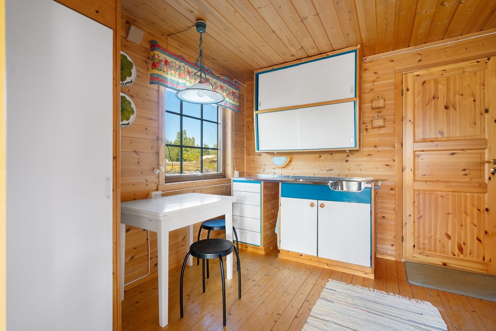 En enkel og sjarmerende kjøkkenkrok med plass til lite spisebord Galleribilde