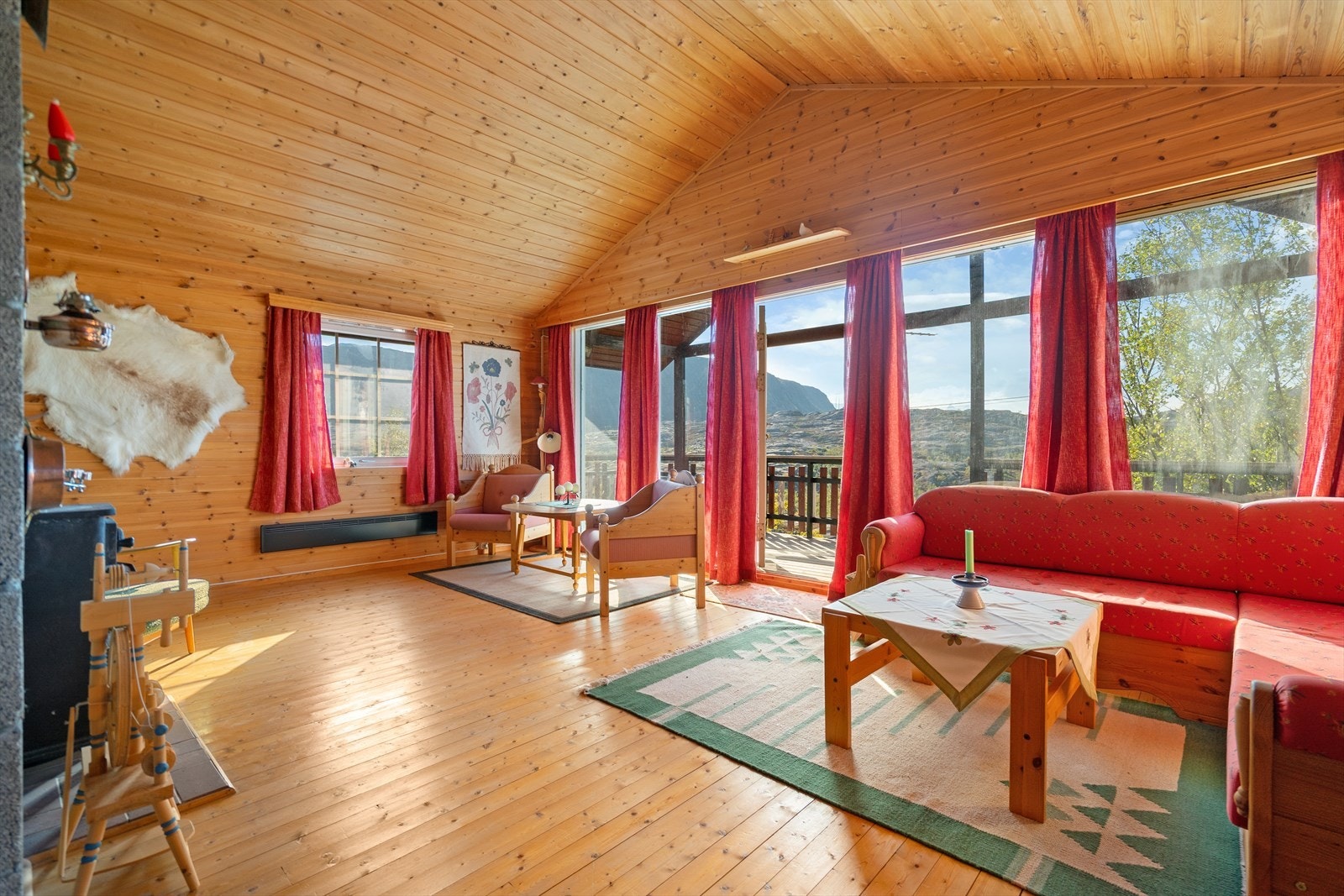 Store vinduer og utgang til terrasse gir deg panoramautsikt over fjell og natur rett utenfor hytta Galleribilde