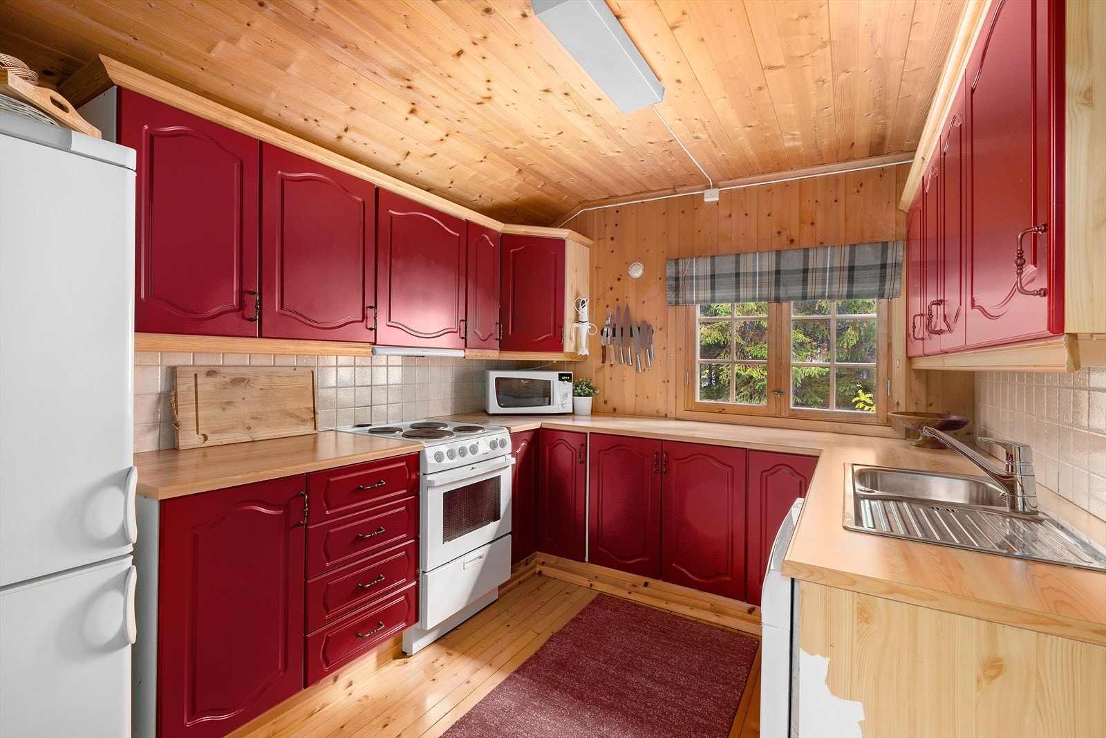 Kjøkkenet har røde speilprofilerte fronter og laminert benkeplate. Galleribilde