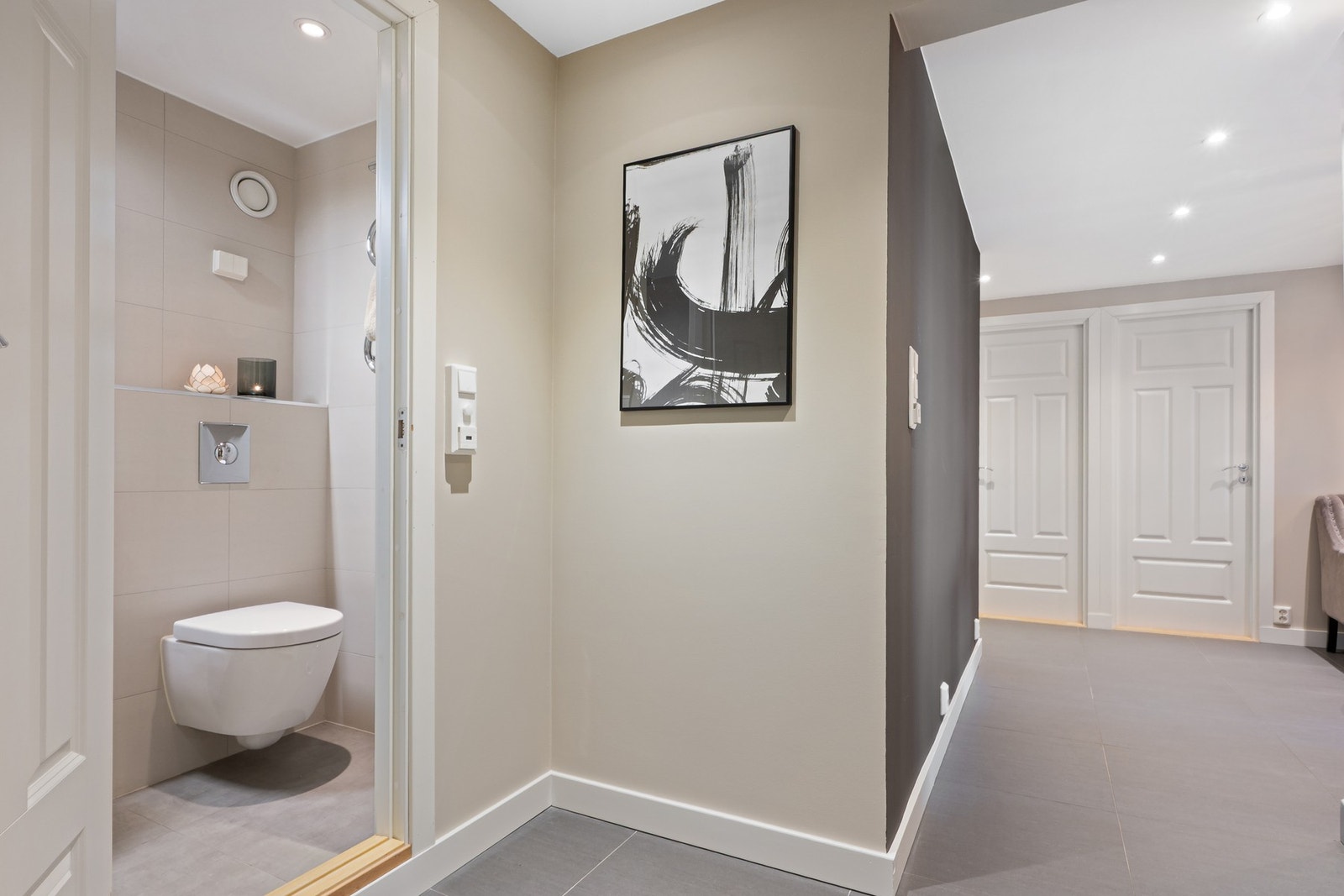 Gjestebad er helfliset og moderne, med dusjhjørne med glassdører, speilskap med belysning og vegghengt toalett. Galleribilde