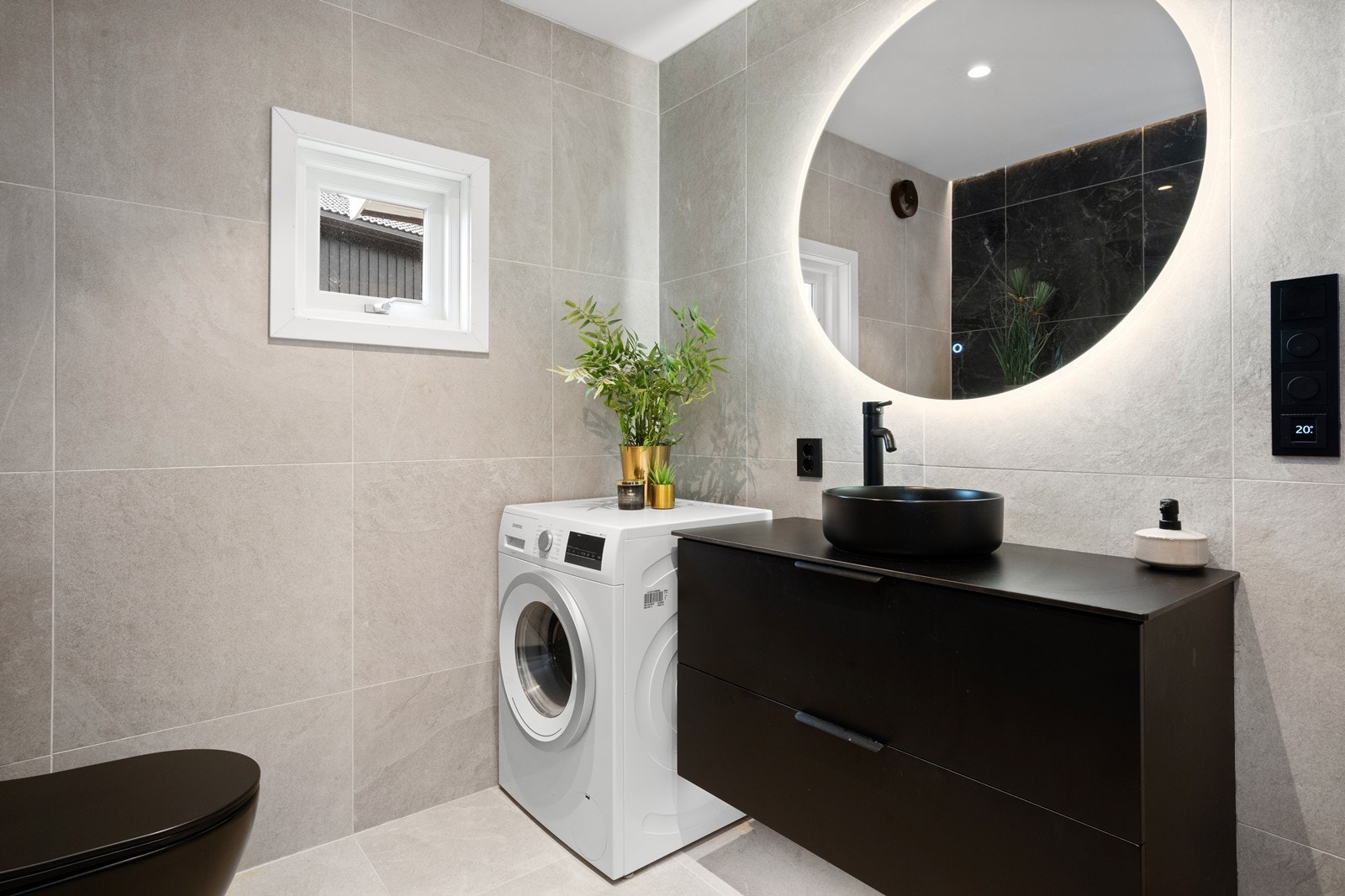 Stilig bad fra 2023 med store fliser samt bl.a. opplegg for vaskemaskin Galleribilde