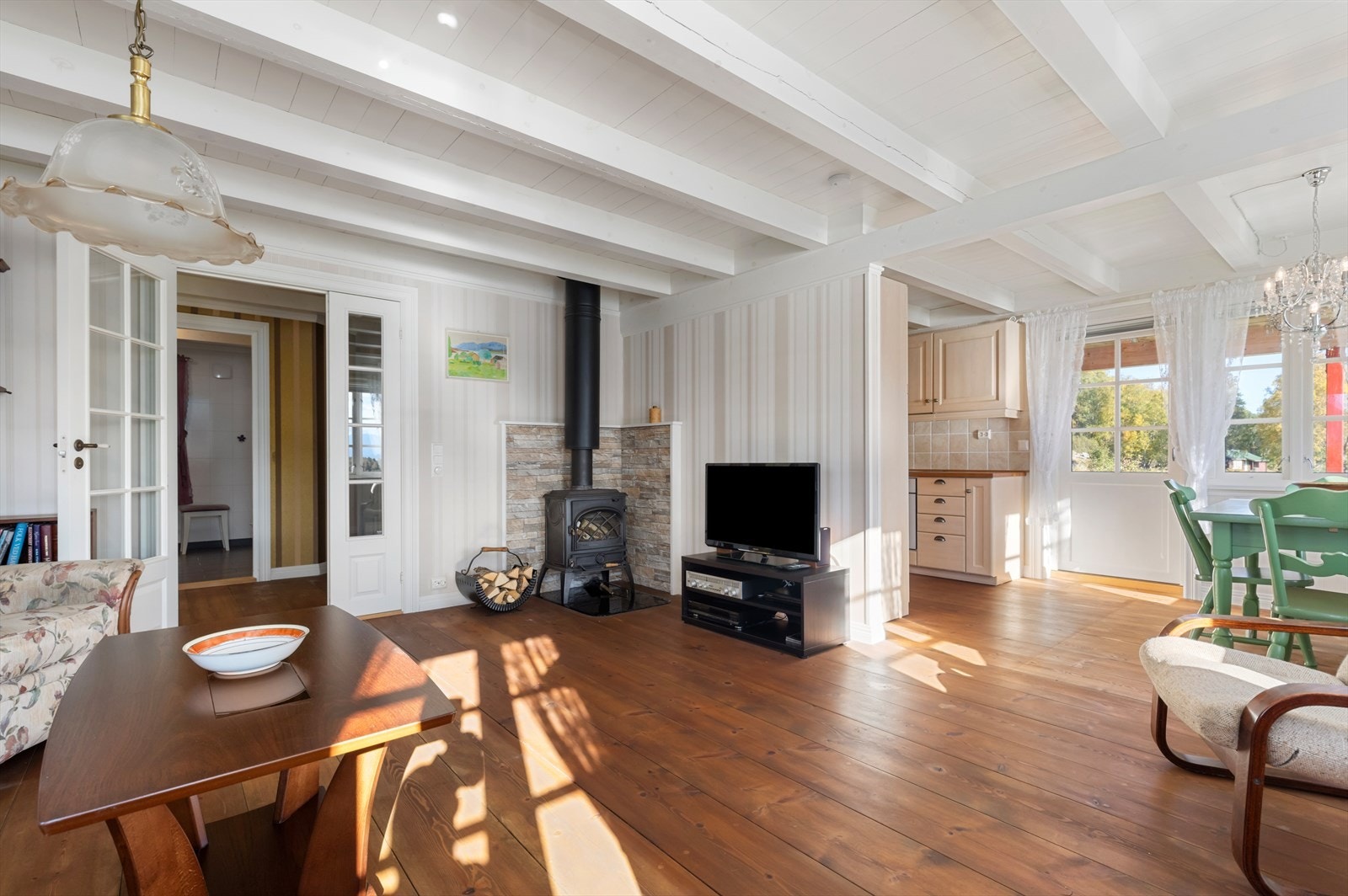 Lys og trivelig stue med god plass til både sittegruppe og spisegruppe | vedovn med stålpipe er montert på stua Galleribilde