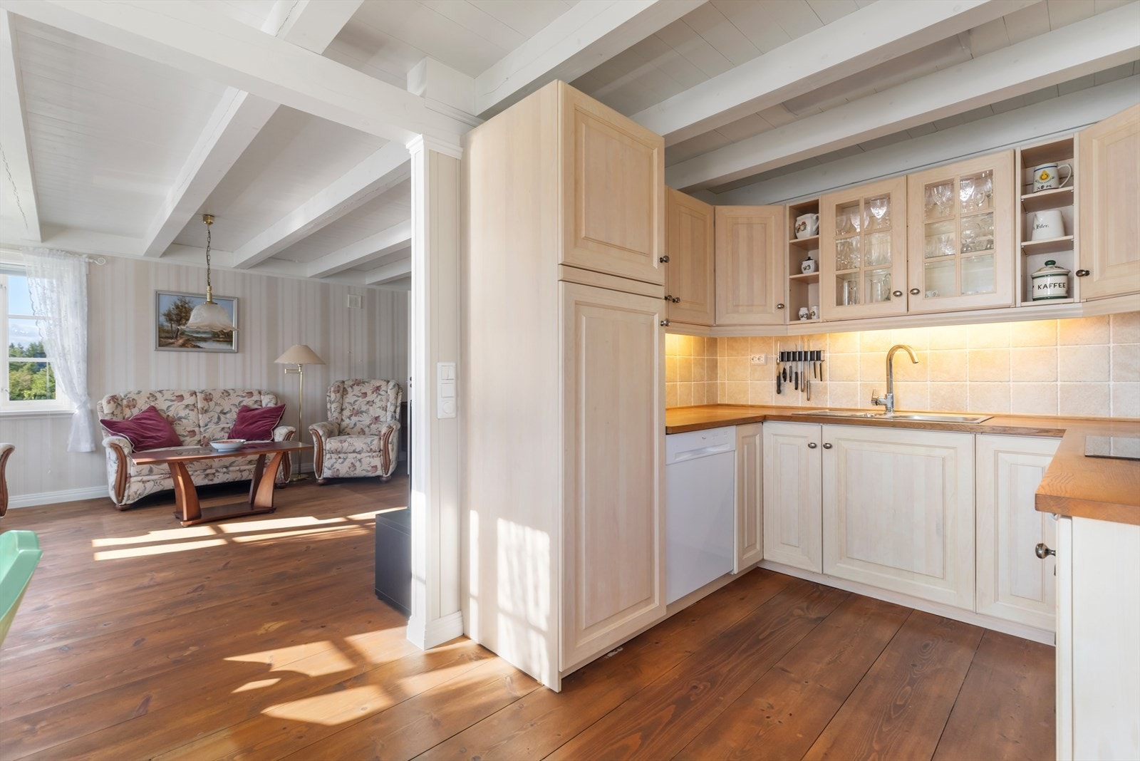 Kjøkkeninnredning med profilerte, lakka skapfronter og med glass | benkeplater av tre med nedfelt vask og platetopp | innredningen er utstyrt med integrert stekeovn og kjøleskap, og det er utsparing for oppvaskmaskin Galleribilde