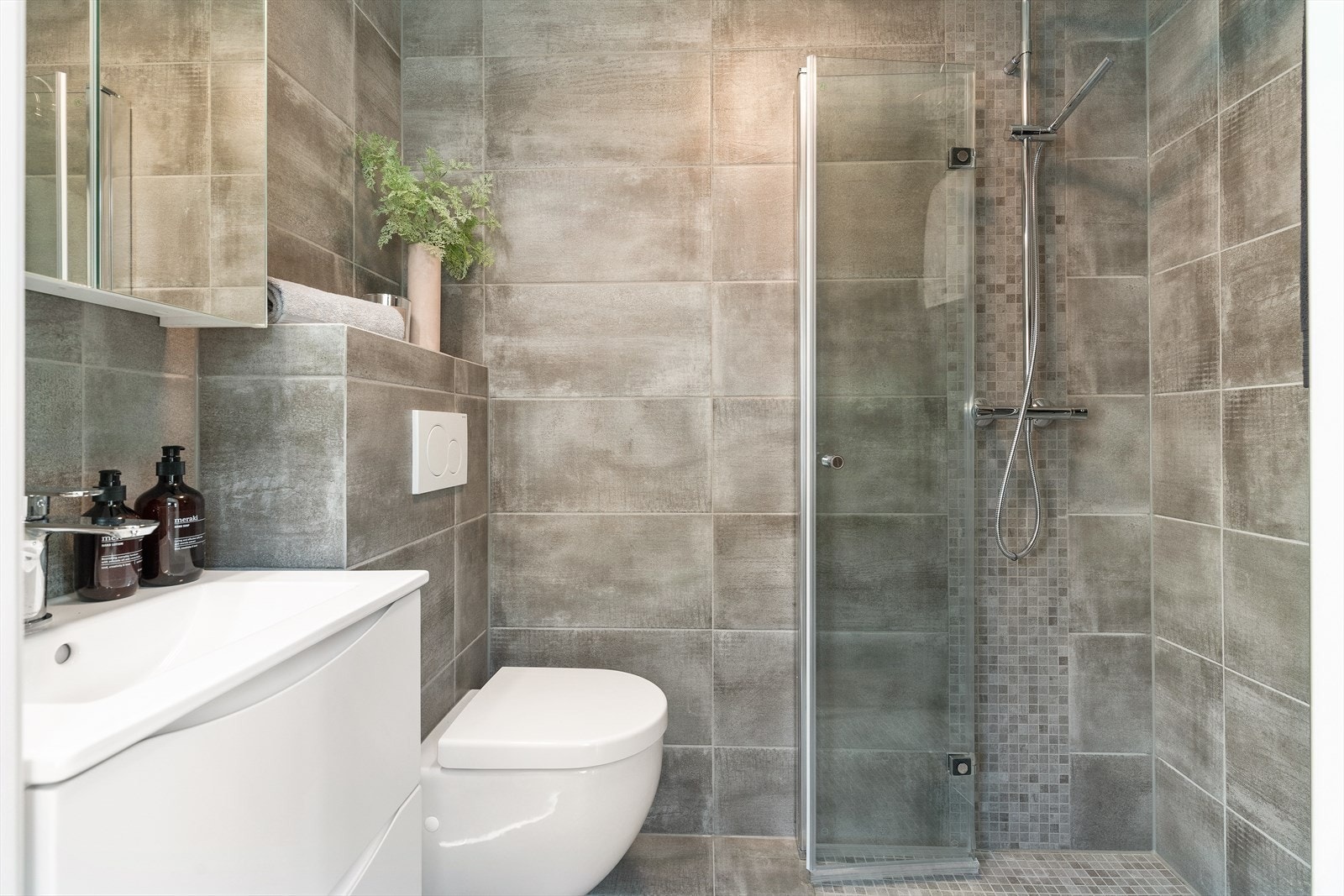 Begge bad er utstyrt med vegghengt toalett, dusjhjørne med svingbare glassdører, og heldekkende servant med tilhørende skuffeinnredning. Galleribilde