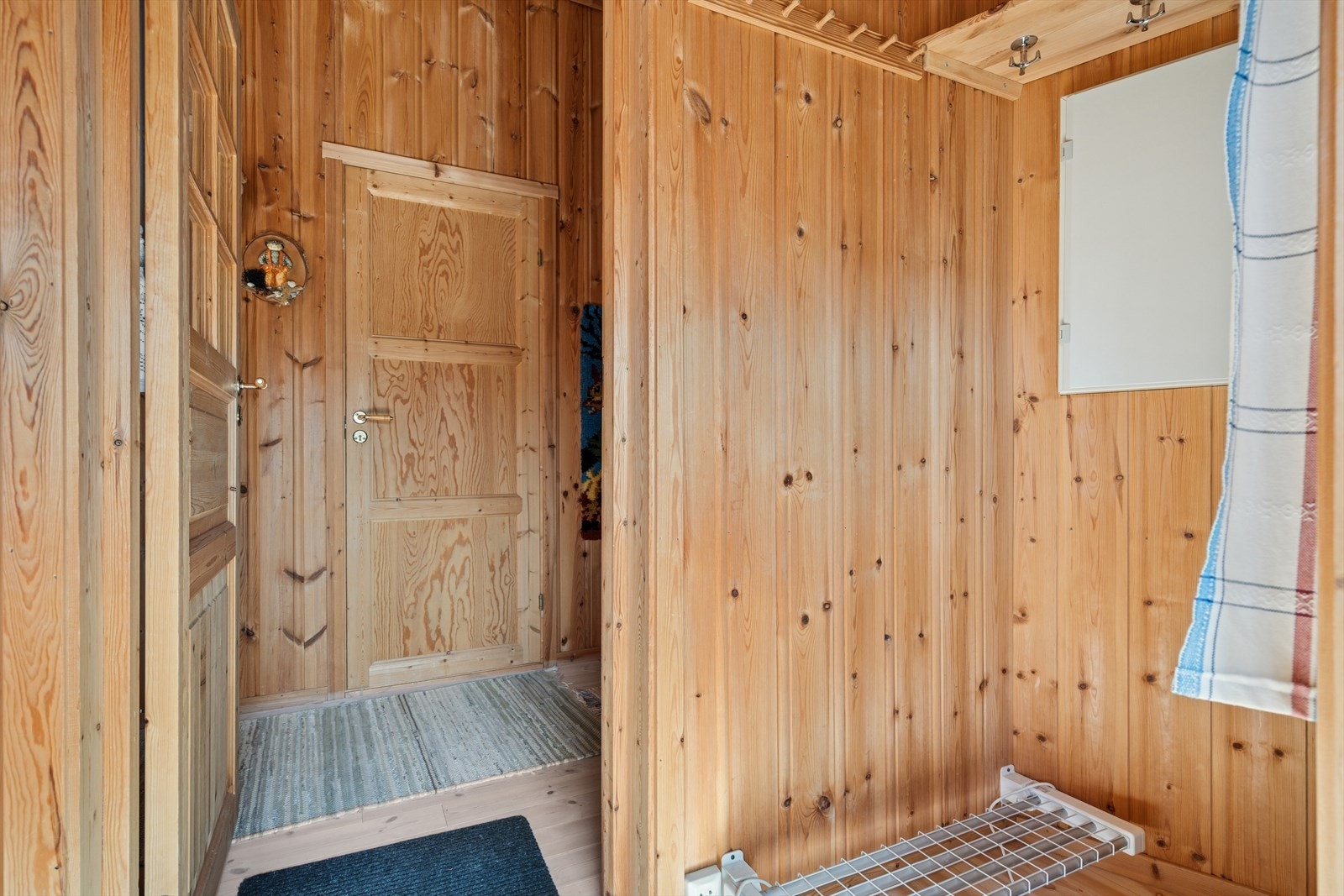 Praktisk vindfang med plass til å henge fra seg yttertøy, samt sko-tørkestativ montert på vegg. Galleribilde