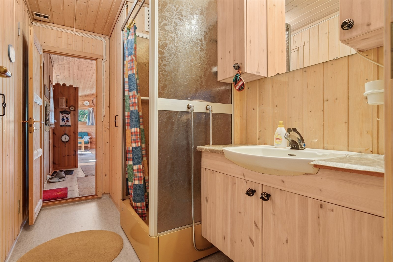 Badet er utstyrt med dusjkabinett og vask med speilskap. Badet gir praktisk adkomst til badstuen samt til to ganger: Den ene gangen fører til soverom og toalettrom, mens den andre gir tilgang til hyttas øvrige rom. Galleribilde
