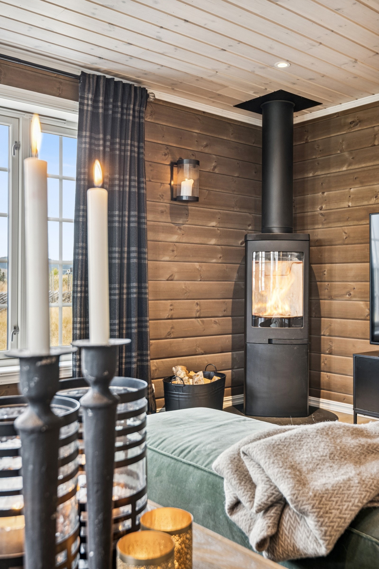 Sofagruppen har god plassering mot en peisvedovn som bidrar til koselig stemning når det knitrer i tørr bjørkeved. Galleribilde