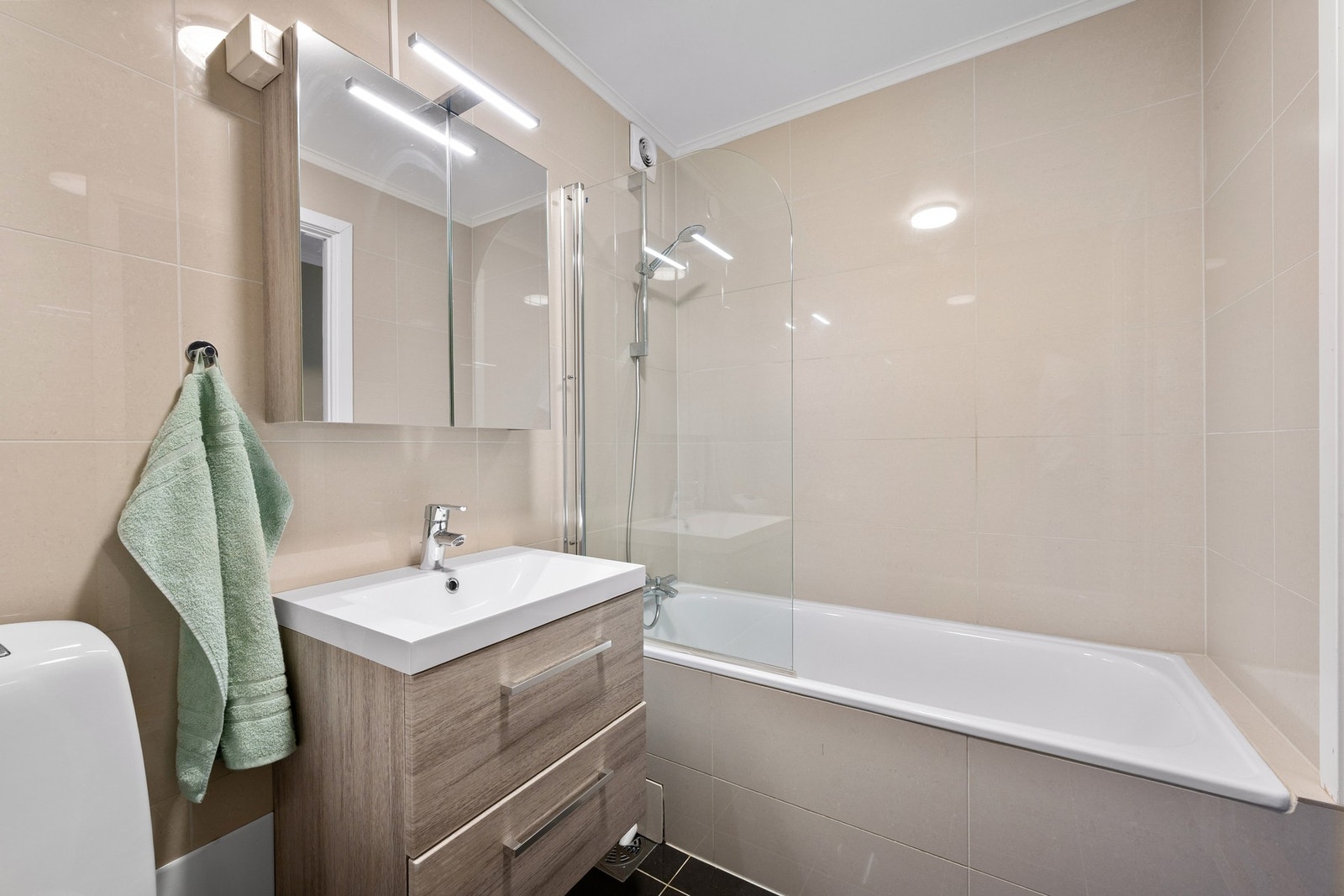 Badet har flislagte gulv og vegger, samt malt tak. Det er installert varmekabler i gulvet som gir behagelig varme, og lys over speil som bidrar til god belysning. Galleribilde