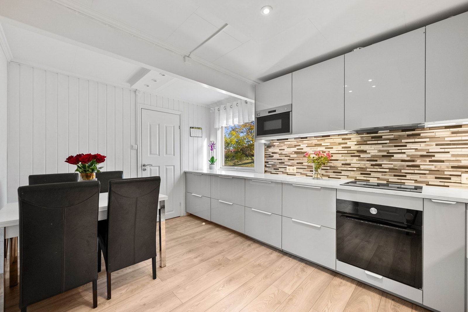 Over benken er det flislagte vegger som gir et rent og moderne uttrykk. Hvitevarer består av kjøl/fryseskap, oppvaskmaskin, komfyr, platetopp, mikrobølgeovn og komfyrvakt. Galleribilde