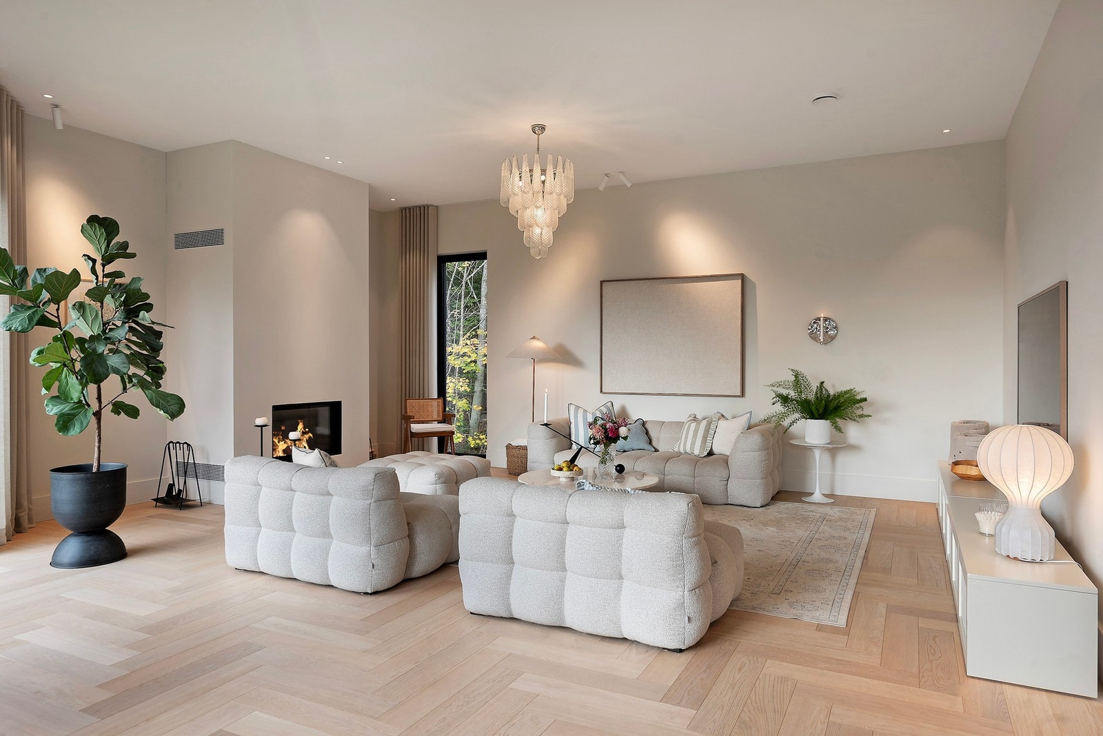 Stort, åpent og luftig oppholdsrom med lune farger og peis som skaper en varm og innbydende atmosfære Galleribilde