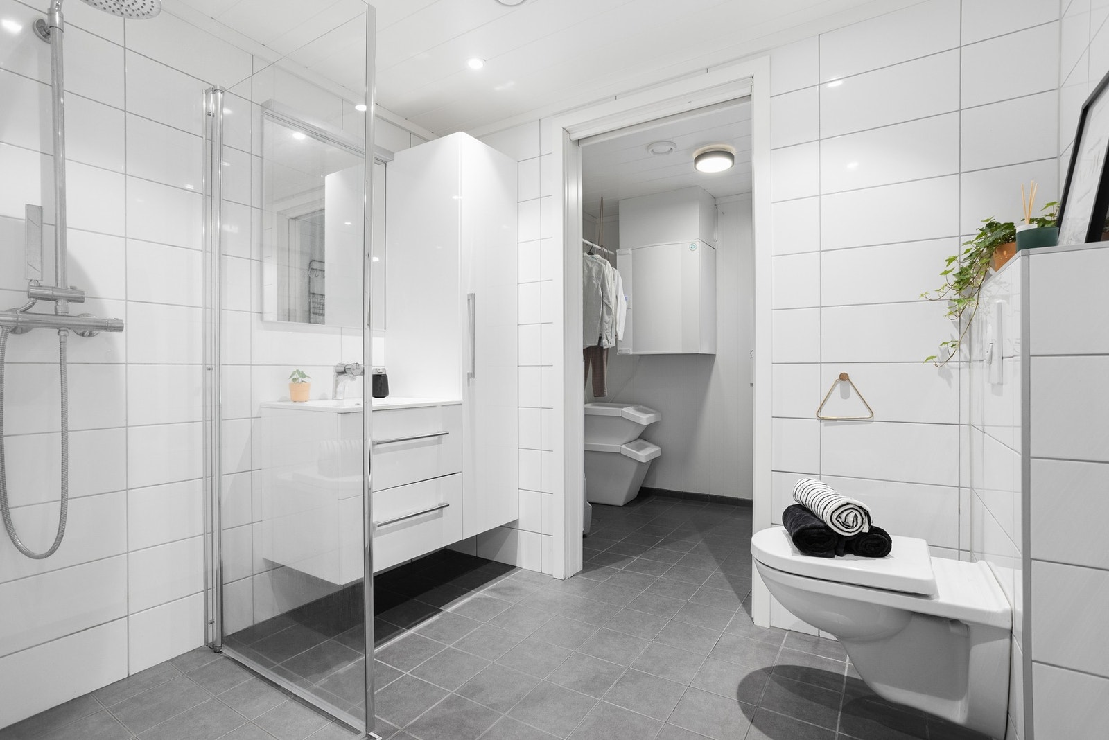 Pent, flislagt bad som er innredet med baderomsinnredning med servant og speil, toalett, dusjnisje med glassvegger, samt opplegg for vaskemaskin. Galleribilde