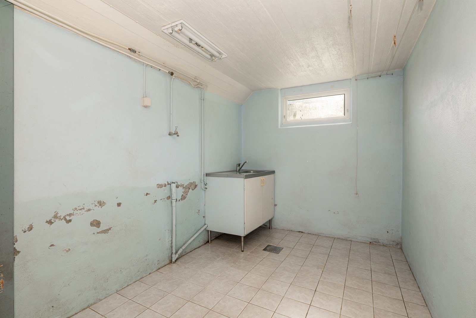 Vaskerom i kjeller med flis på gulv, malt betong på vegg samt malt betong i himling. Galleribilde