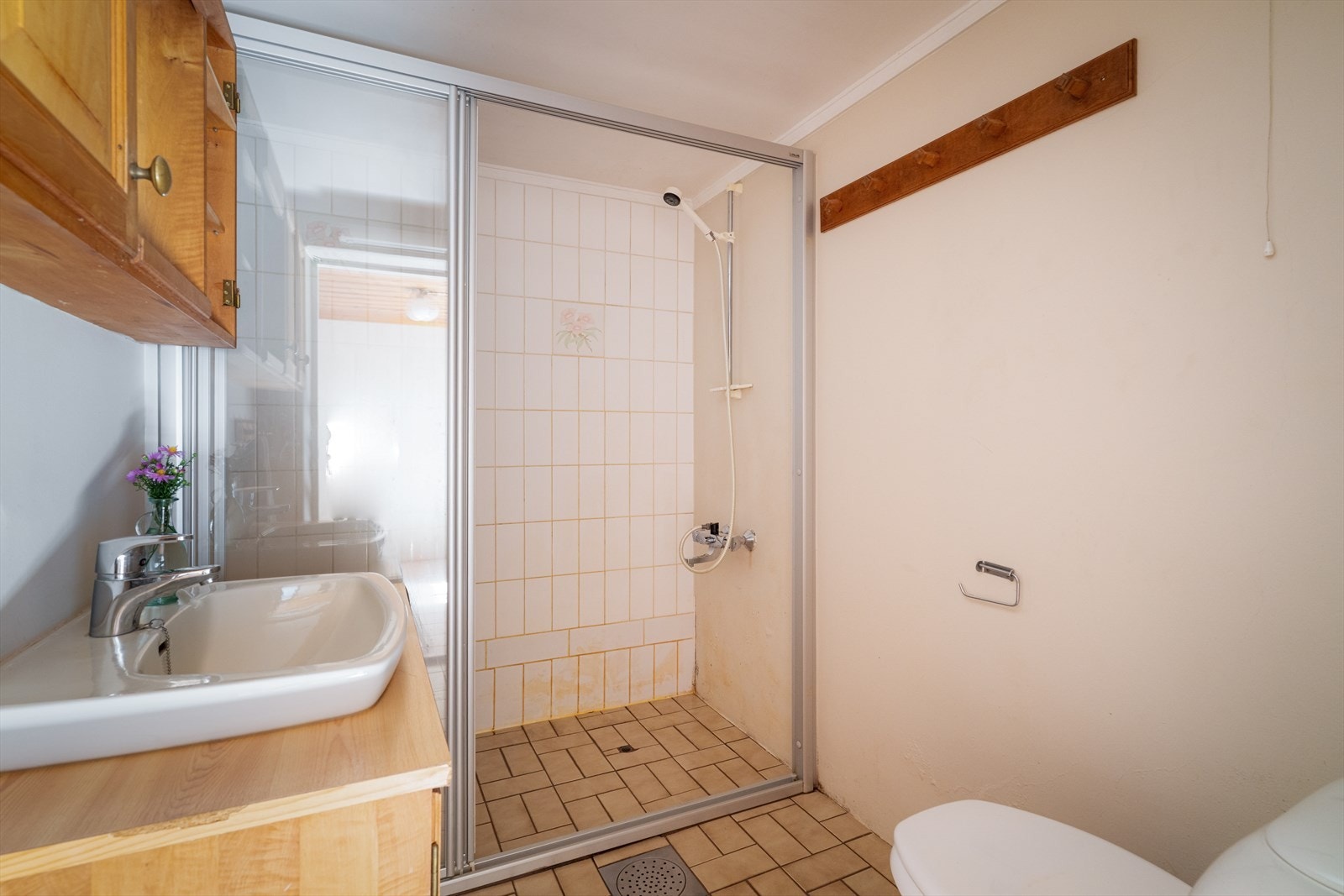 Bad i kjeller av eldre årgang som inneholder gulvmontert toalett, servant med underskap, overskap og dusjnisje. Galleribilde