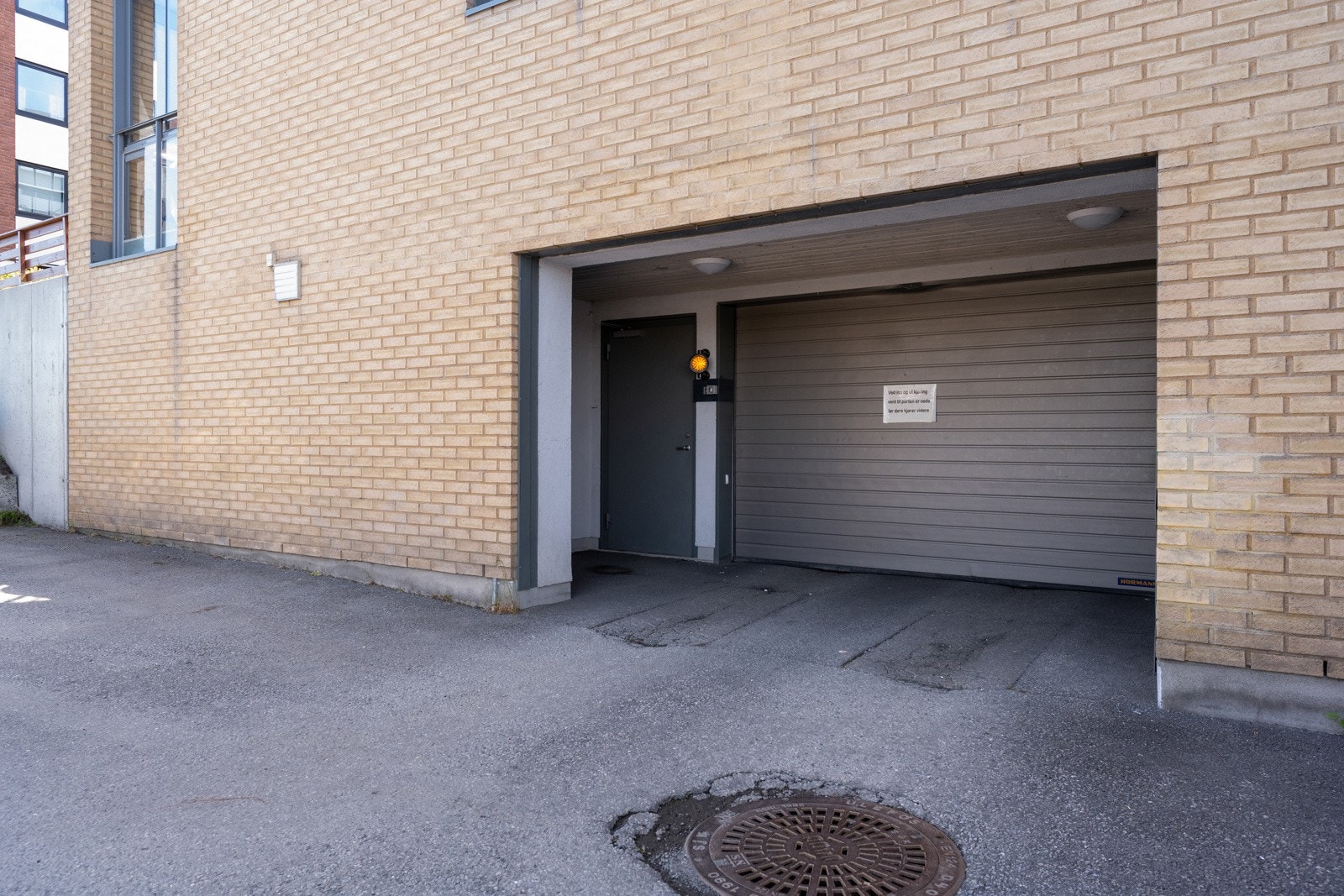 Innkjørsel til felles garasjeanlegg i kjelleren - her er det en biloppstillingsplass som følger leiligheten. Galleribilde