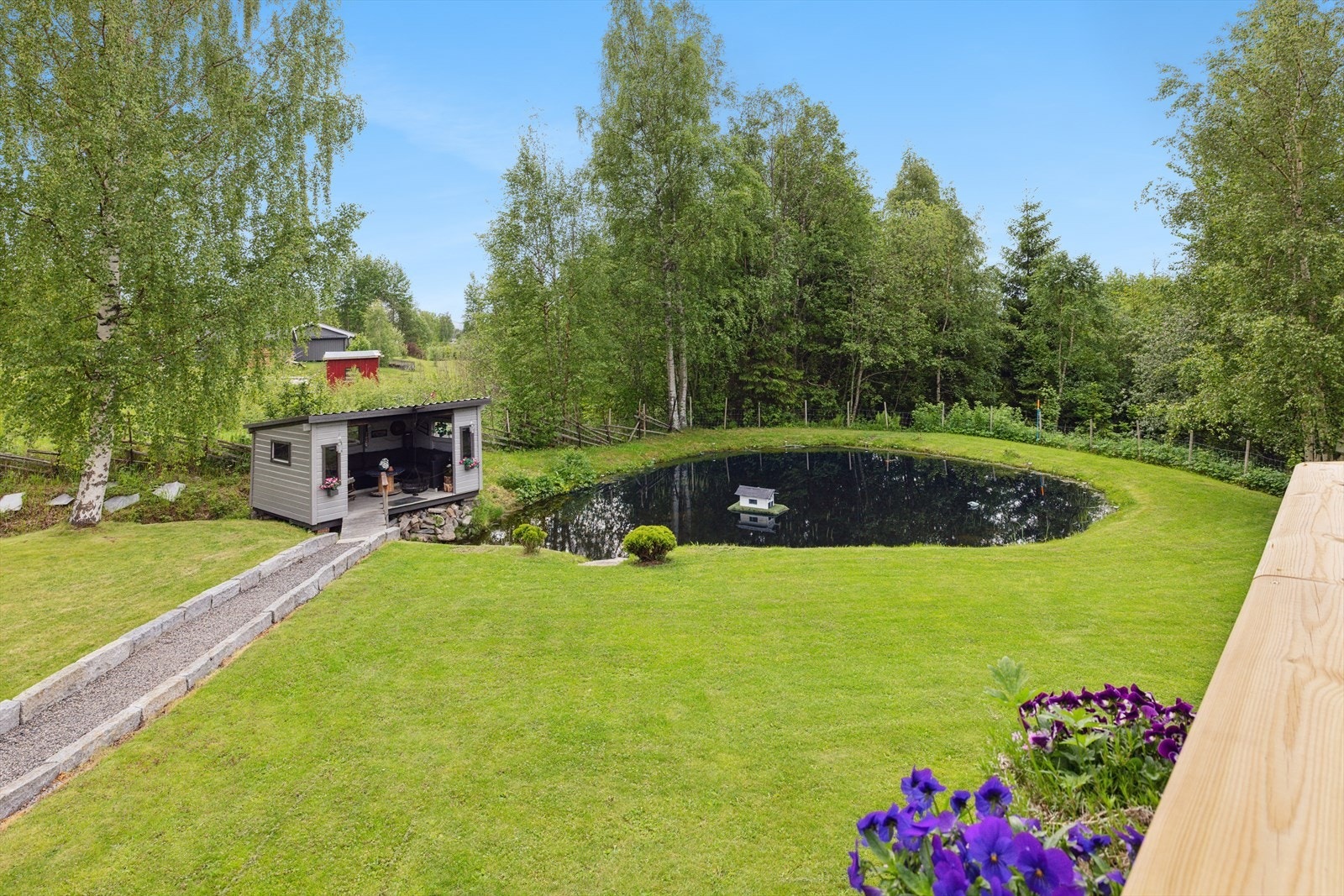 Tomten er hellende og har et vakkert hageanlegg med plen og variert beplantning. Galleribilde