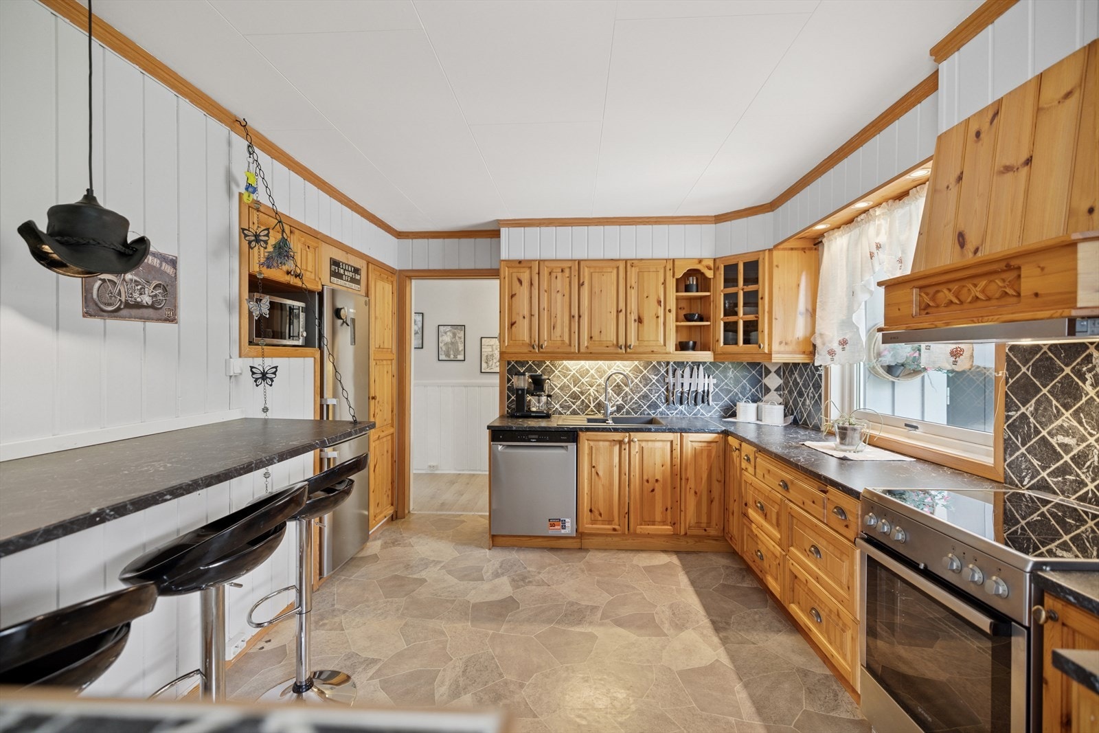 Kjøkkeninnredningen har ukjent alder og er utført med brune, profilerte fronter og laminert benkeplate med nedfelt kjøkkenkum. Galleribilde