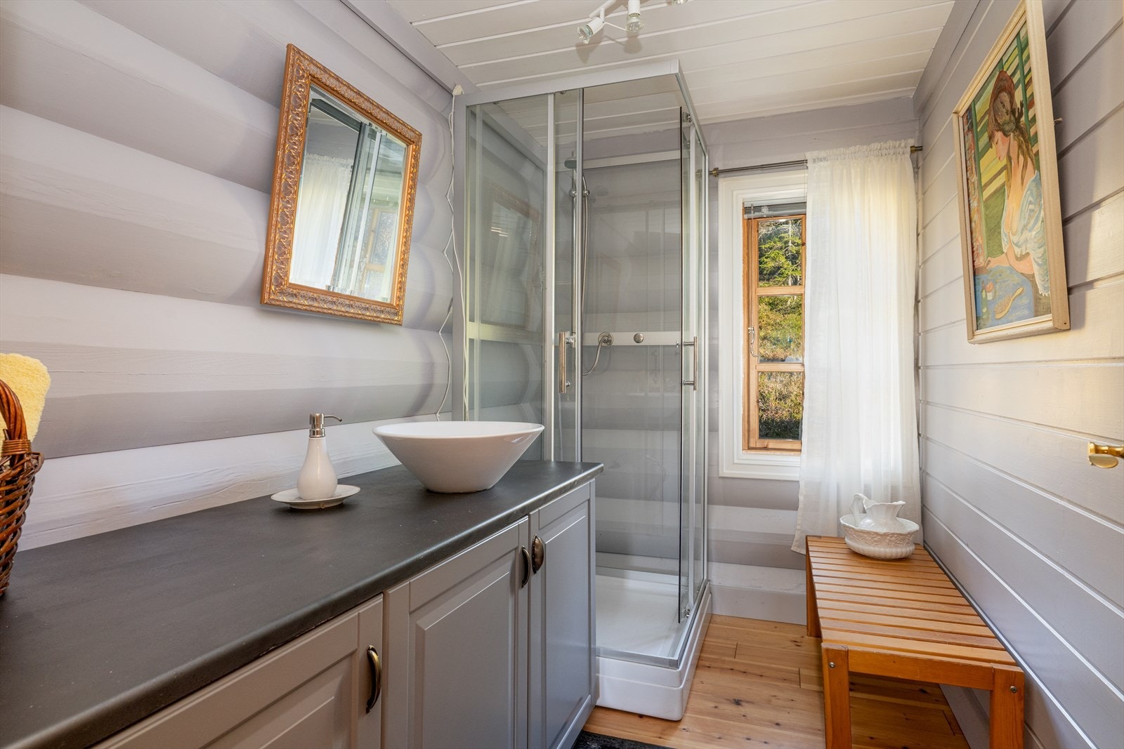 Badet inneholder innredning med toppmontert servant og dusjkabinett. Galleribilde