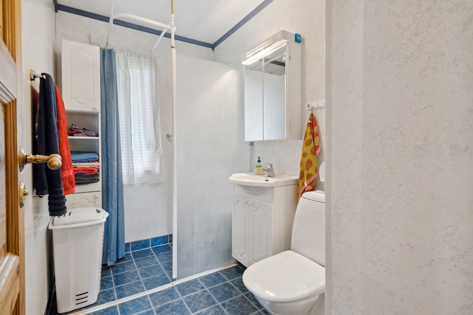 Flislagt bad 1.etasje fra 2000 med varmekabler i gulv. Innredet med vegghengt nedfelt servant, høyskap, dusjvegg i glass og gulvmontert toalett. Galleribilde