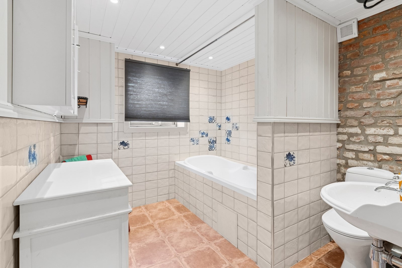 Romslig, flislagt baderom i kjeller med servant, toalett og badekar. God oppbevaringsplass i innredning. Galleribilde