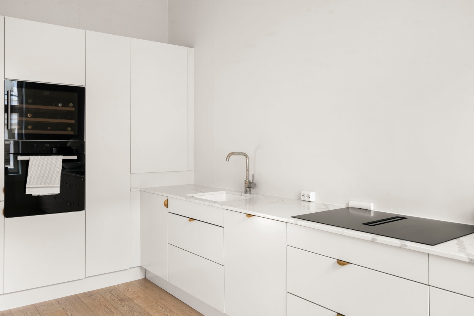 Integrert induksjonsplatetopp med ventilator, stekeovn, vinskap, oppvaskmaskin og kombiskap for kjøl/frys. Galleribilde