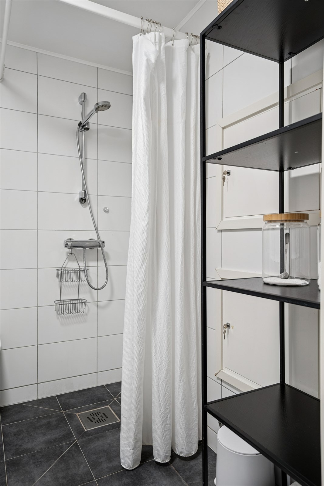 Baderommet er utstyrt med vegghengt toalett og dusj med forheng direkte på gulv. Galleribilde