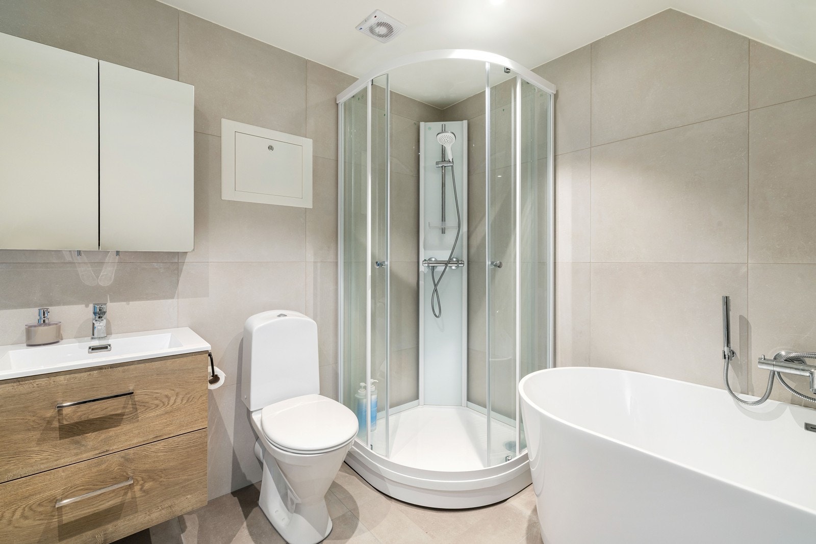 Flislagt med varmekabler og innredet med dusjkabinett, badekar, toalett og servant med innredning. Galleribilde