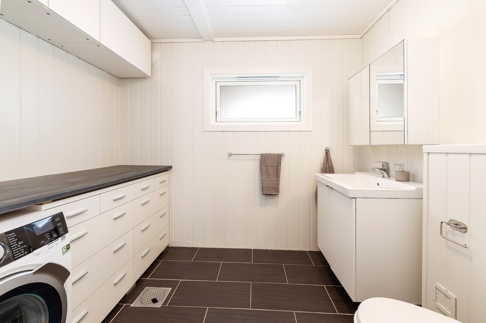 Vaskerommet er innredet med benkeskap, toalett og vask. Det er opplegg for vaskemaskin. Galleribilde