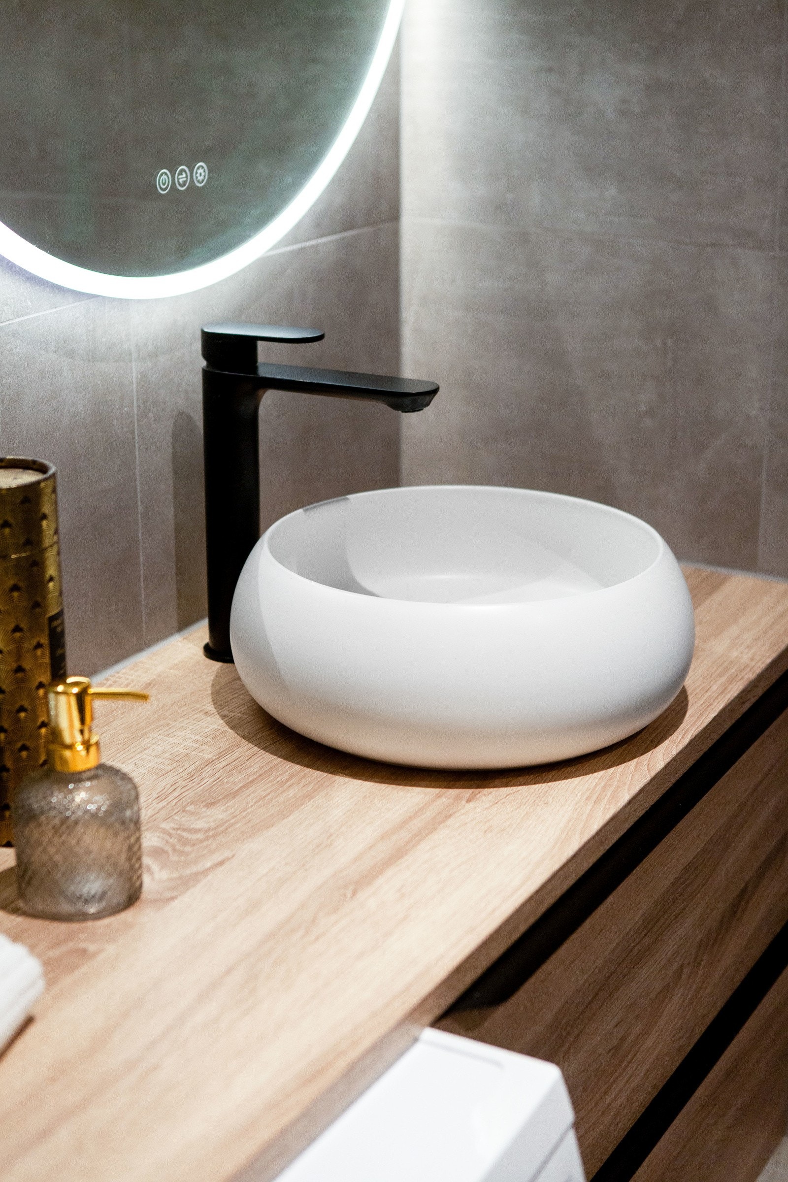 Innredningen består av en lekker bolleservant på eikefarget skuffeseksjon, rundt speil med integrert belysning, et veggmontert toalett med spylekran, og et dusjhjørne med glassvegg, regnfallsdusj, hånddusj og shamponisje. Galleribilde