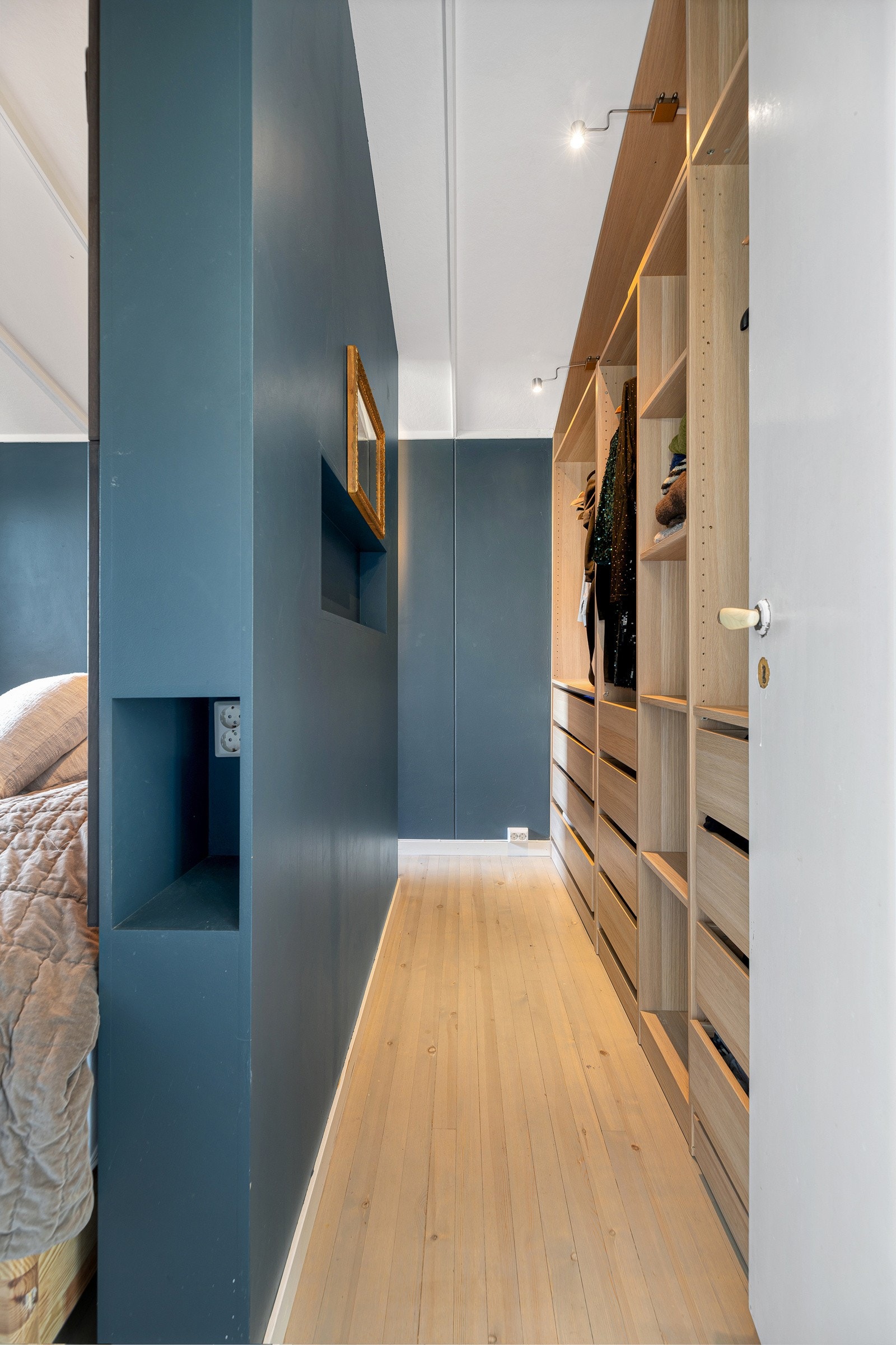 En stilig sengegavl med rom for oppbevaring fungerer som romdeler, og på den ene siden har hovedsoverommet et walk-in closet. Galleribilde