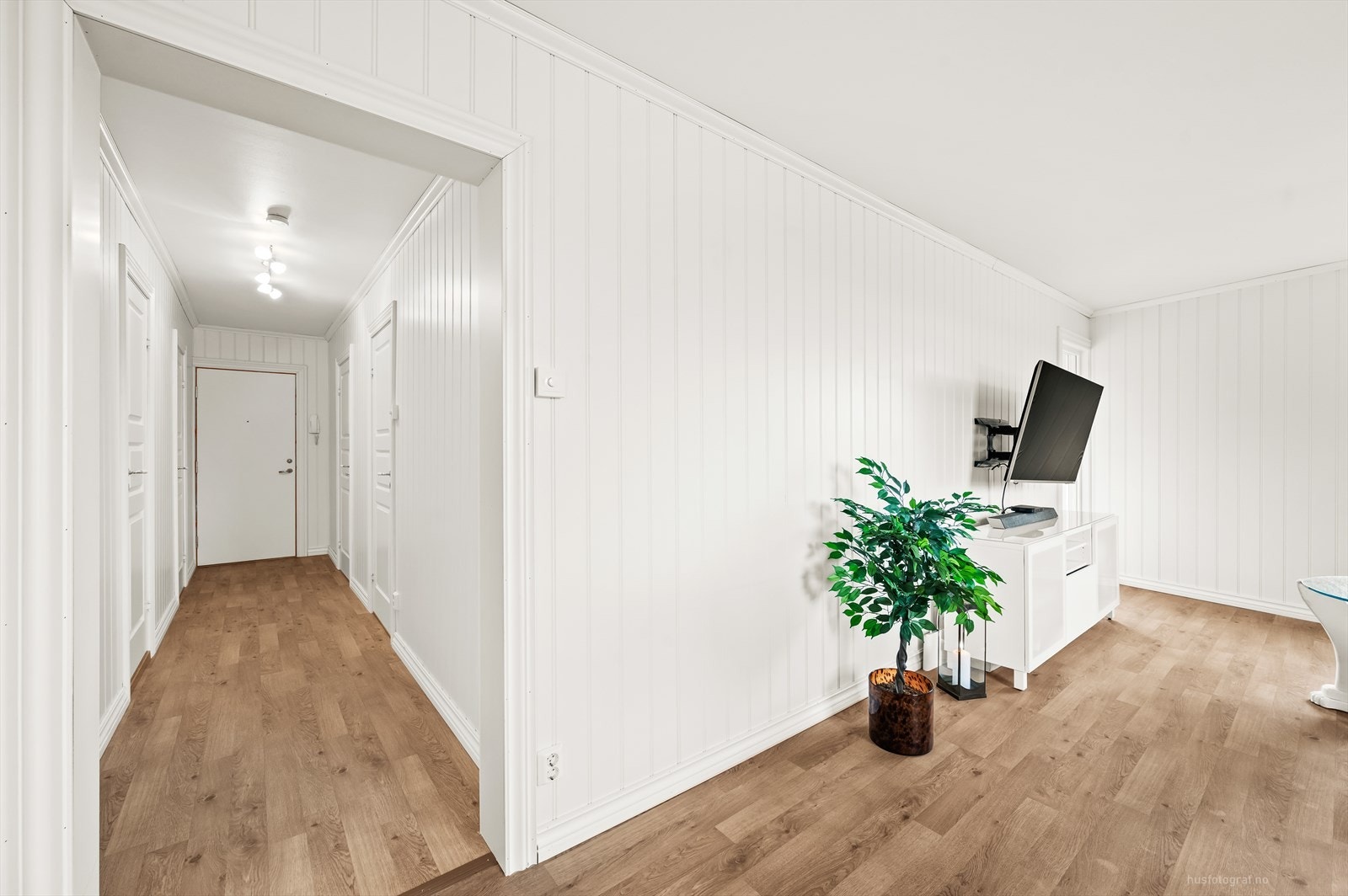 Lys og delikat stue med parkett på gulv og hvitmalte panel på vegger. Galleribilde