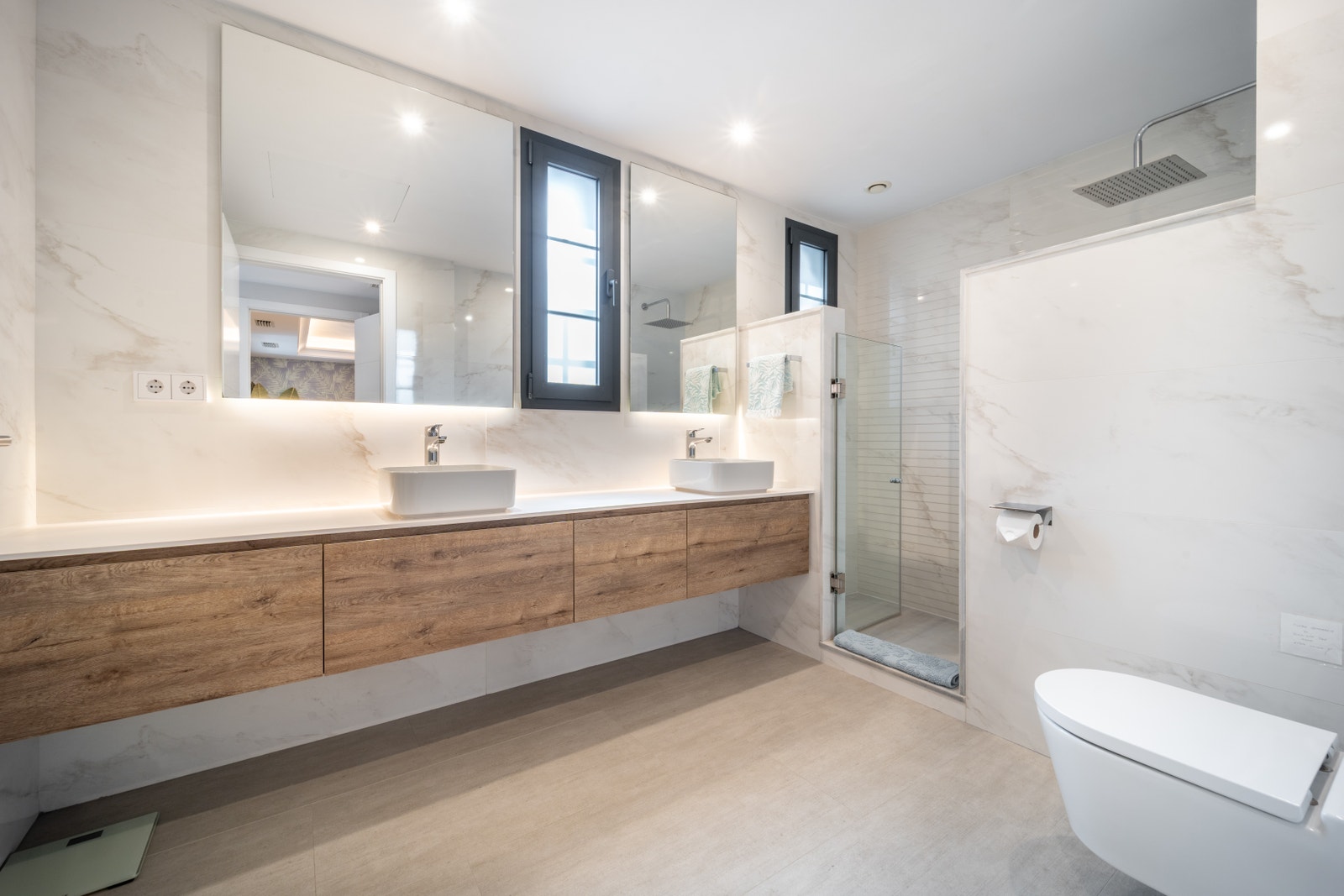 Experience luxury in Casa Salma’s spacious primary bedroom ensuite, featuring a large twin sink vanity, a generous walk-in shower, and windows that flood the space with natural light. Thoughtfully designed for comfort and understated elegance, this bathro Galleribilde