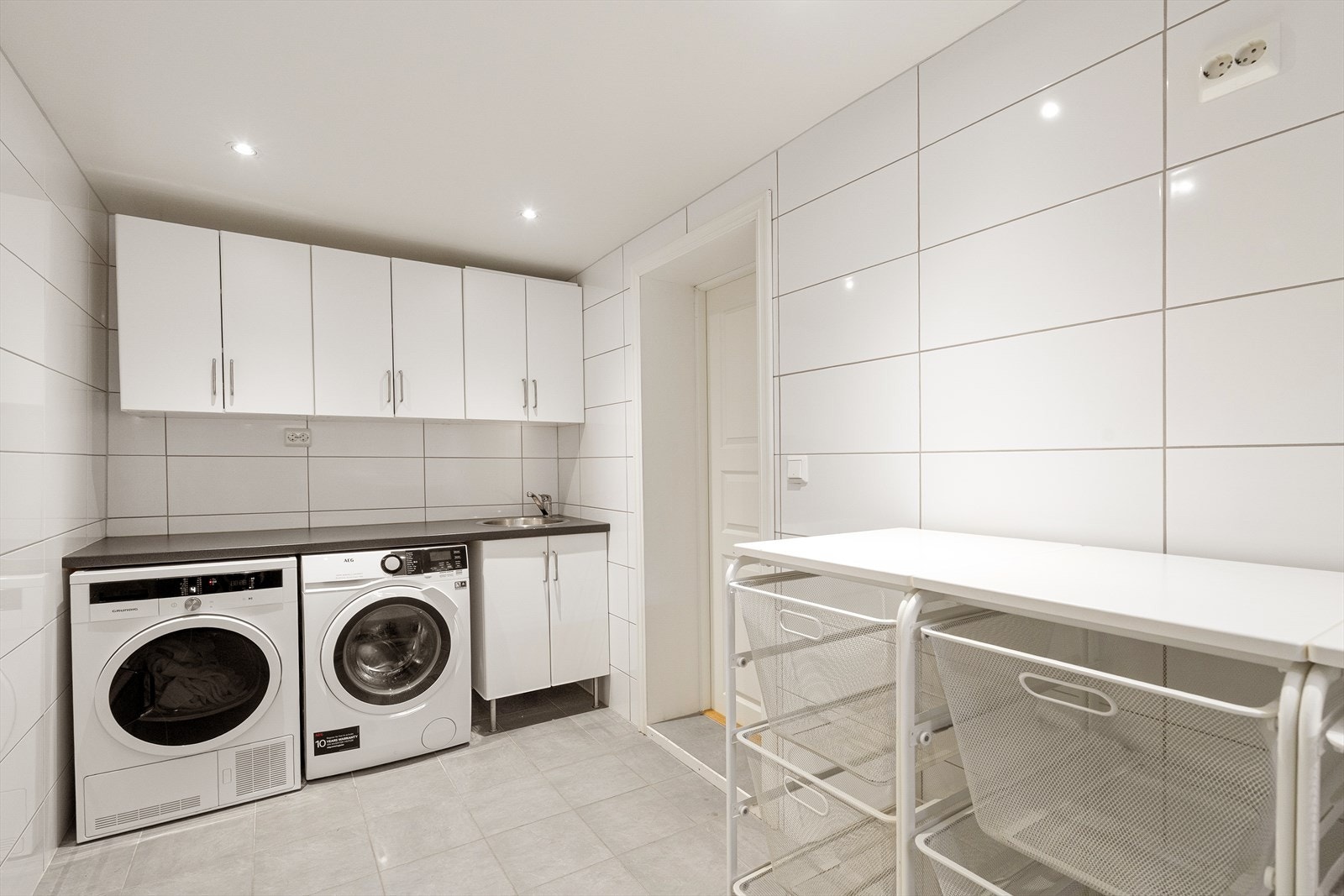 Praktisk flislagt vaskerom med opplegg for vaskemaskin og tørketrommel. Her er det også rikelig med lagringsplass i innredningen. Galleribilde