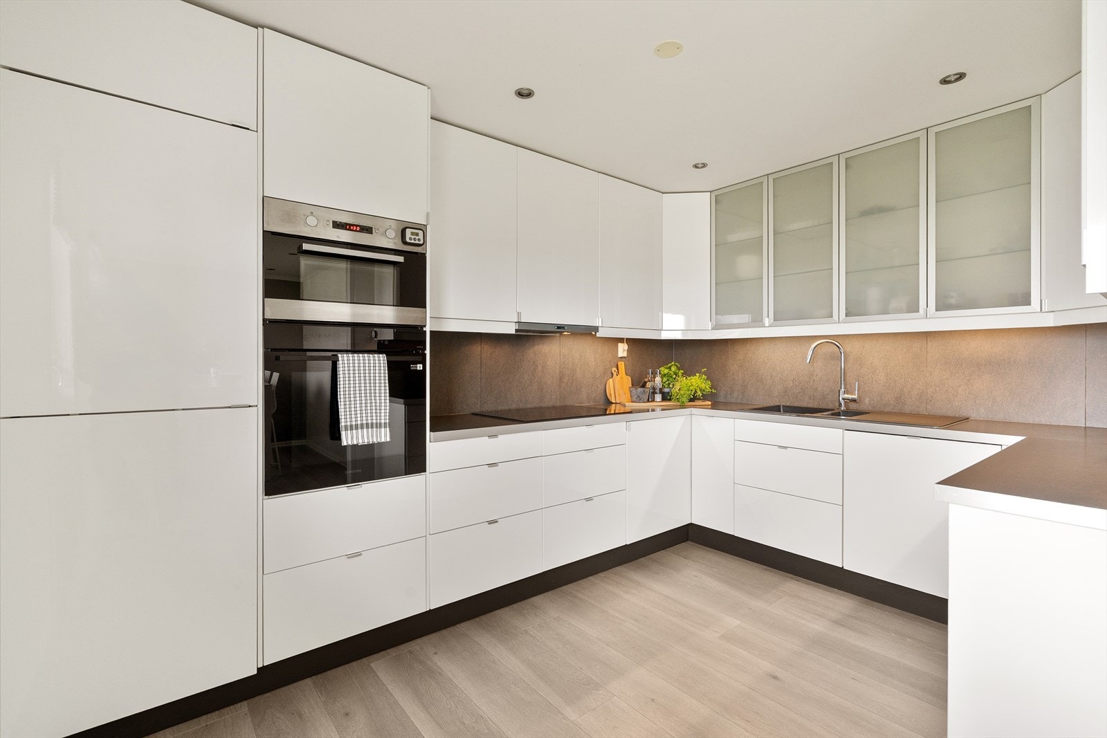 Lekkert og moderne kjøkken med hvite fronter og mørk benkeplate. Galleribilde