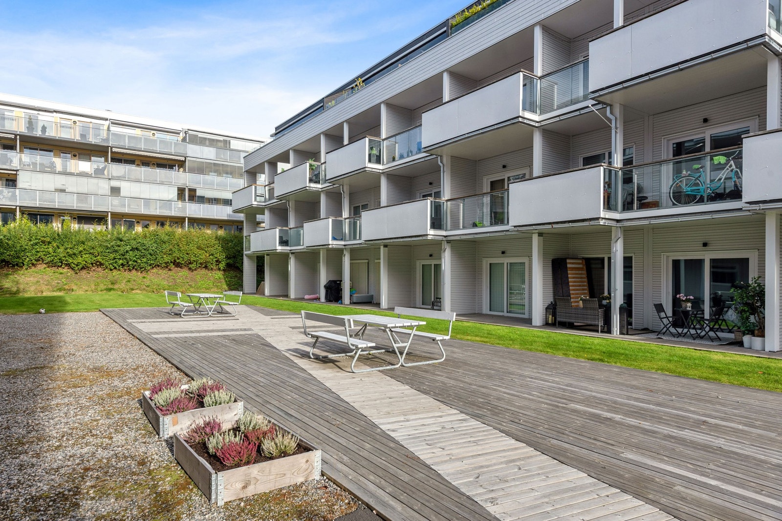 Felles grøntareal med plen, prydbusker og felles terrasse med sittebenker, en hyggelig møteplass. Galleribilde