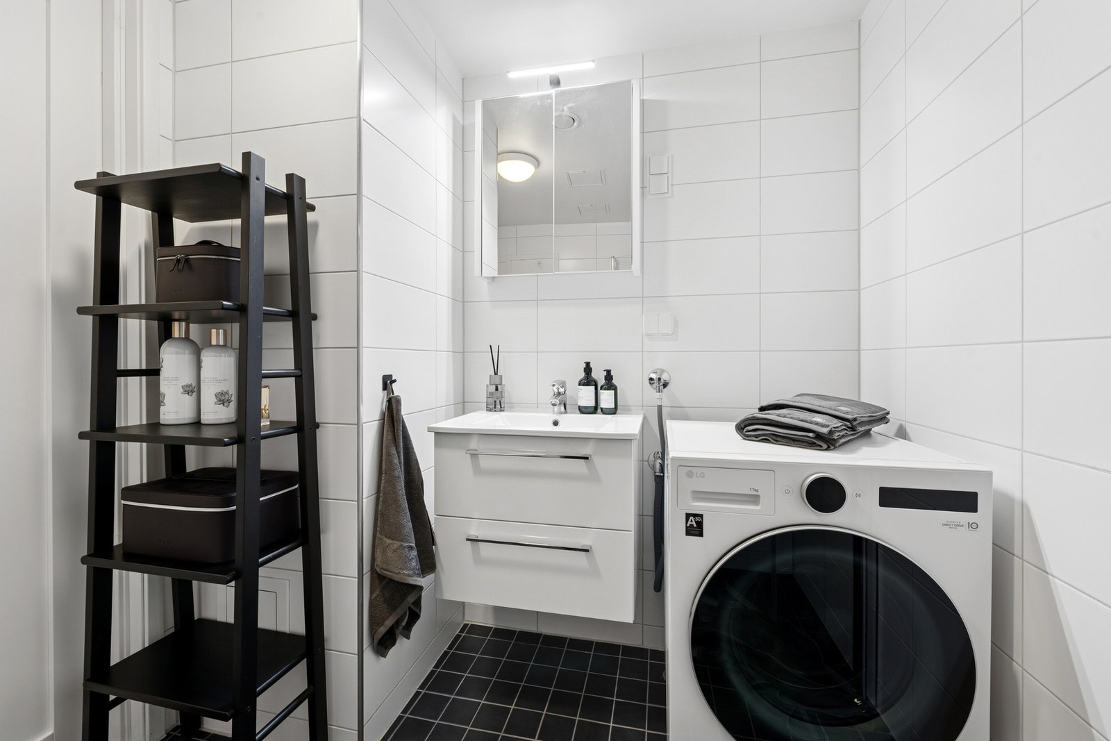 Innredning med vegghengt toalett, servantmøbel med skuffer, speilskap med overlys og et dusjhjørne med innfellbare glassdører. Galleribilde